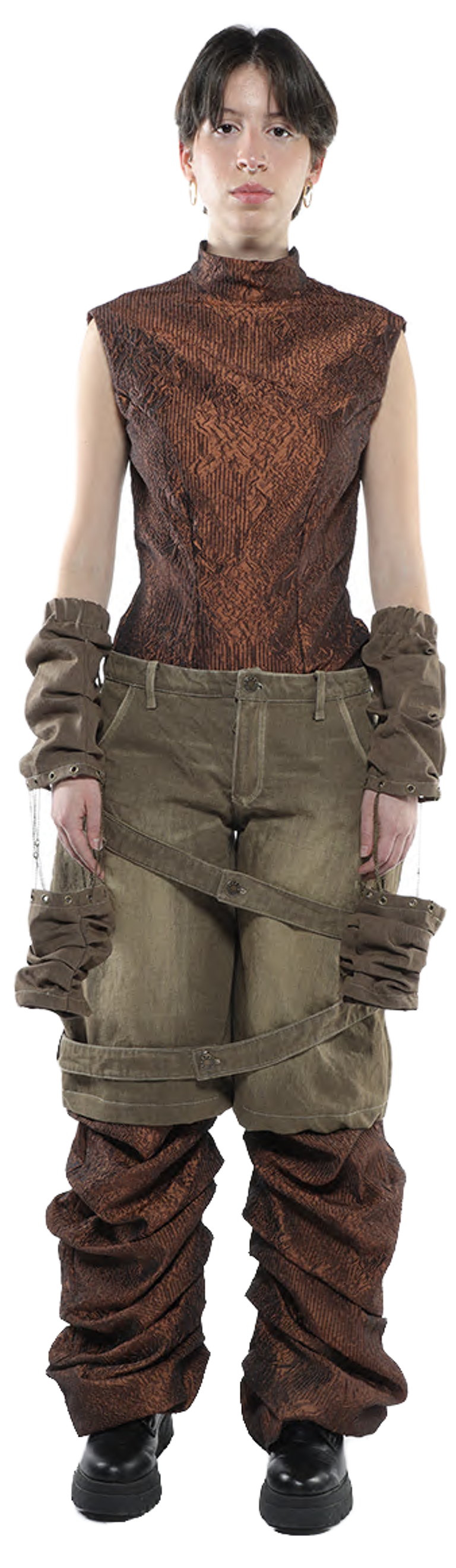 A person with short dark hair is shown from the knees up wearing a copper-colored sleeveless top, olive-green pants with brown fabric wrapped around the legs and arms, and dark shoes.