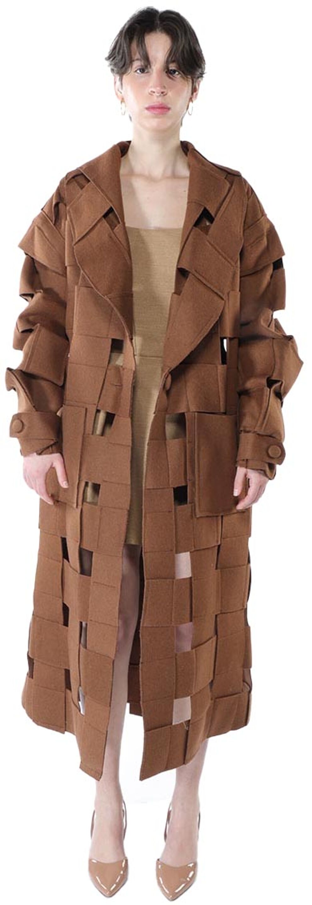A brown, long-sleeved coat with cut-out squares is modeled by a person wearing nude heels and a nude dress.