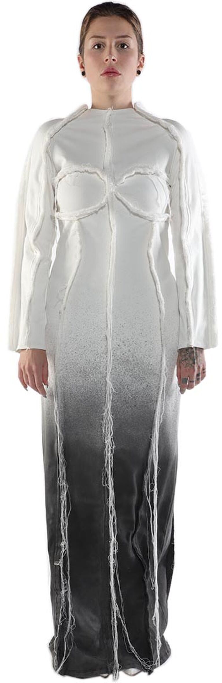 A woman with light skin and dark hair is shown wearing a long, white and black ombre dress with frayed edges.