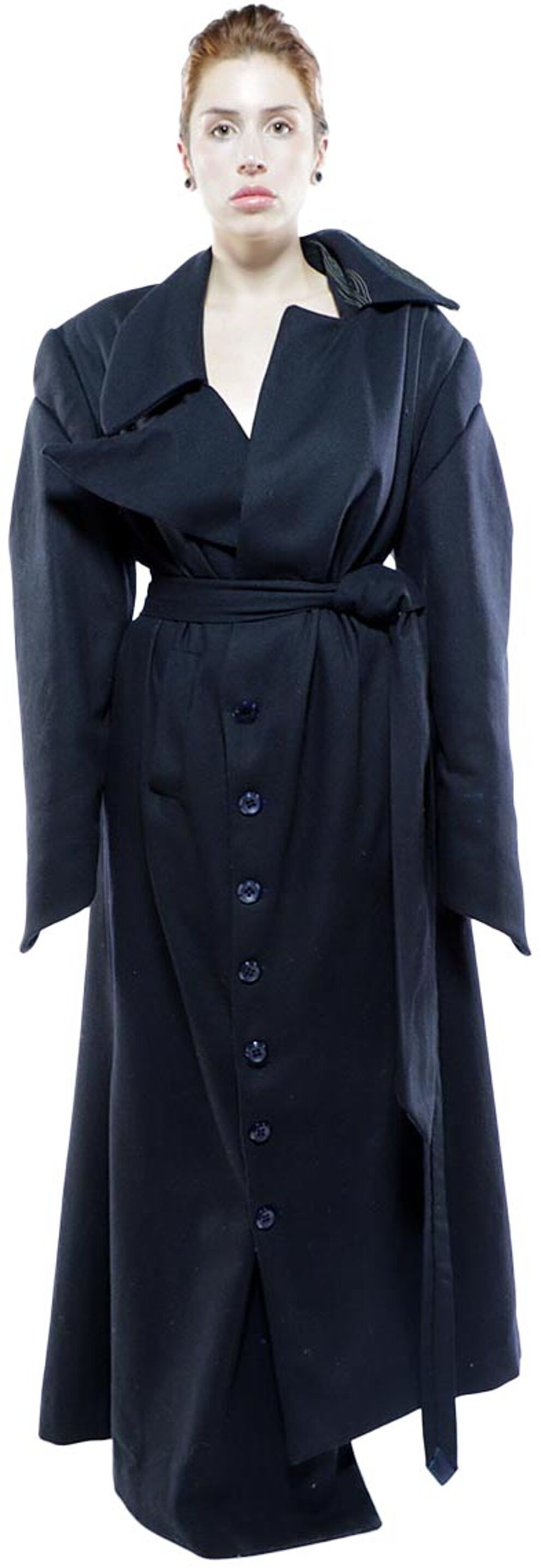 A woman with red hair wears a long, dark-blue coat with large sleeves, a belted waist, and a button-front closure.