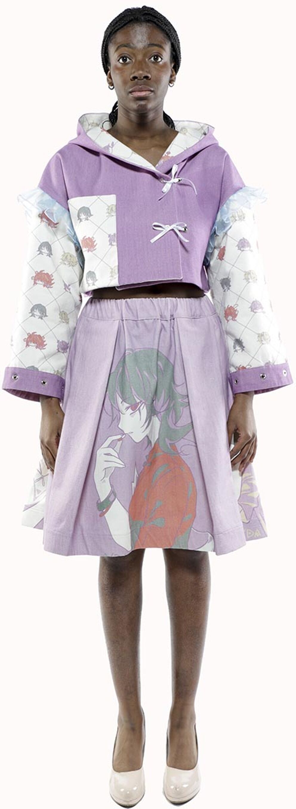 A model with dark skin and a dark head wrap wears a lavender and white hooded jacket and pleated skirt with an anime-style graphic, and lavender high heels.
