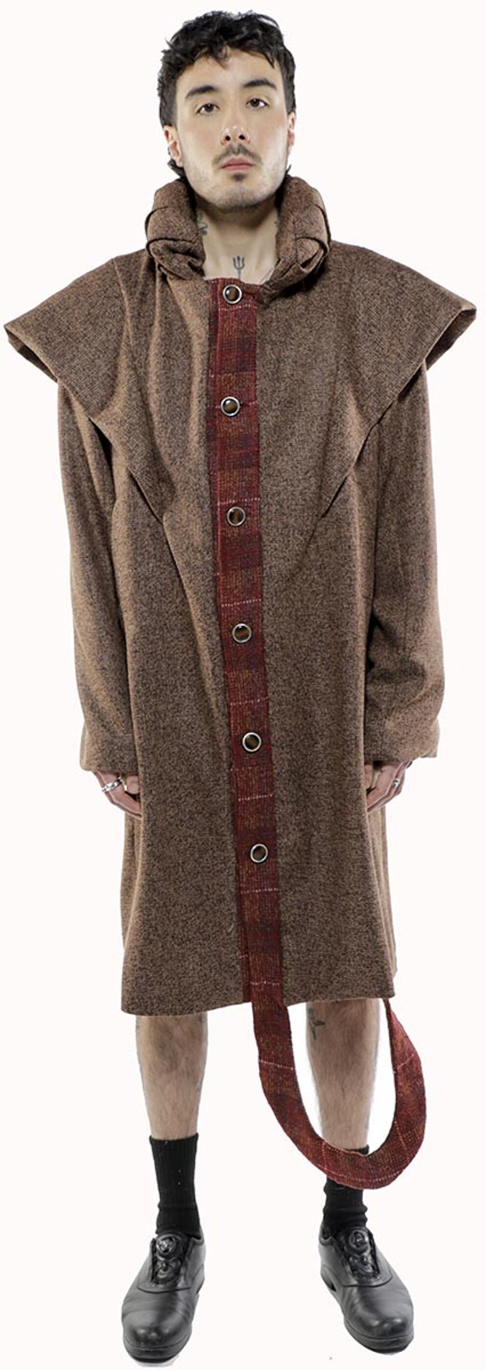 A man with dark hair and a neutral expression models a long brown coat with a red and brown patterned center panel and matching long belt.