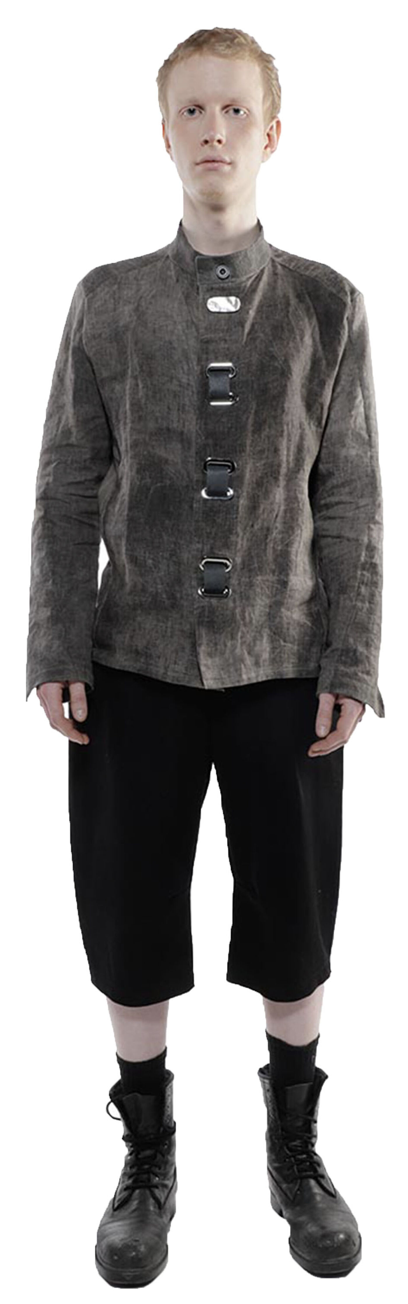 A pale-skinned person with short reddish-blond hair wears a gray long-sleeved shirt with metallic accents, black shorts, and black combat boots.
