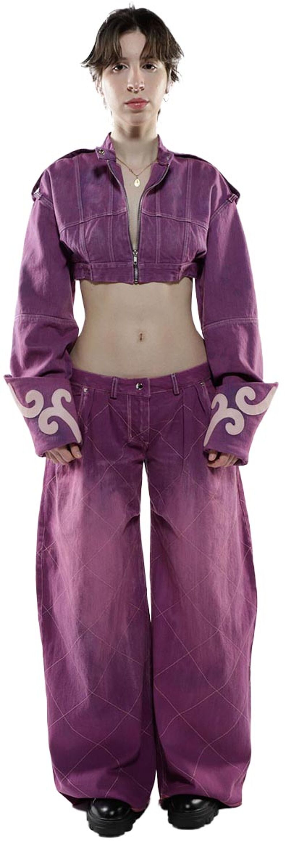 A young woman with short brown hair models a purple denim cropped jacket and wide-leg pants, both adorned with pale pink embroidered swirls at the cuffs.