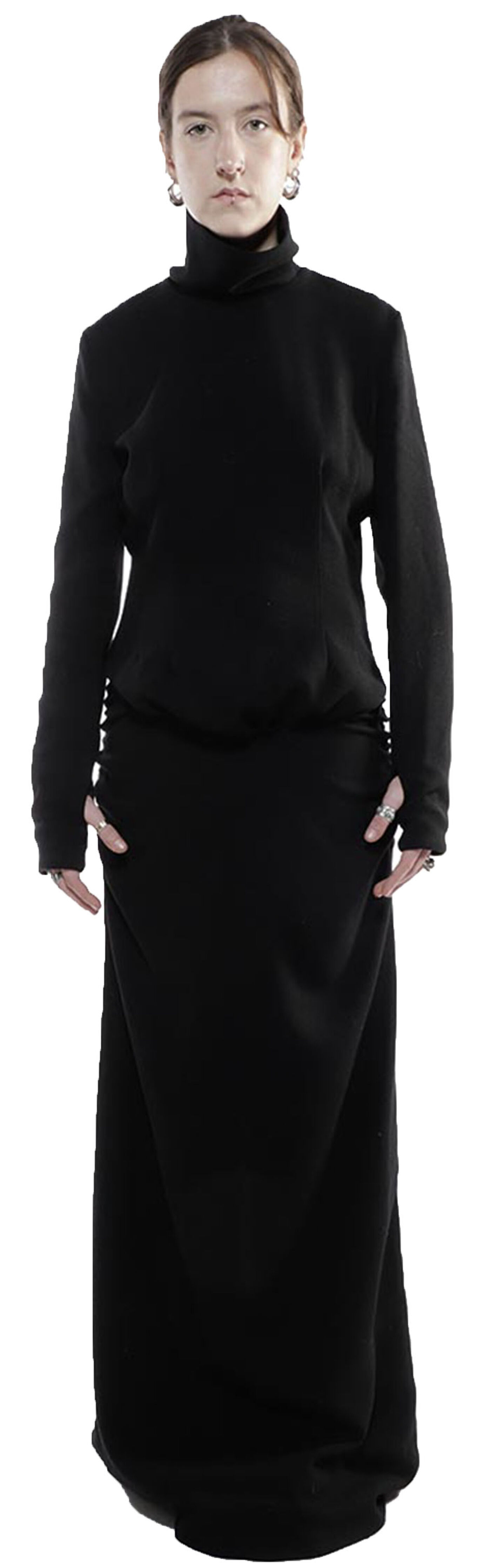 A young woman with shoulder-length brown hair wears a long-sleeved, black turtleneck dress that falls to her ankles.