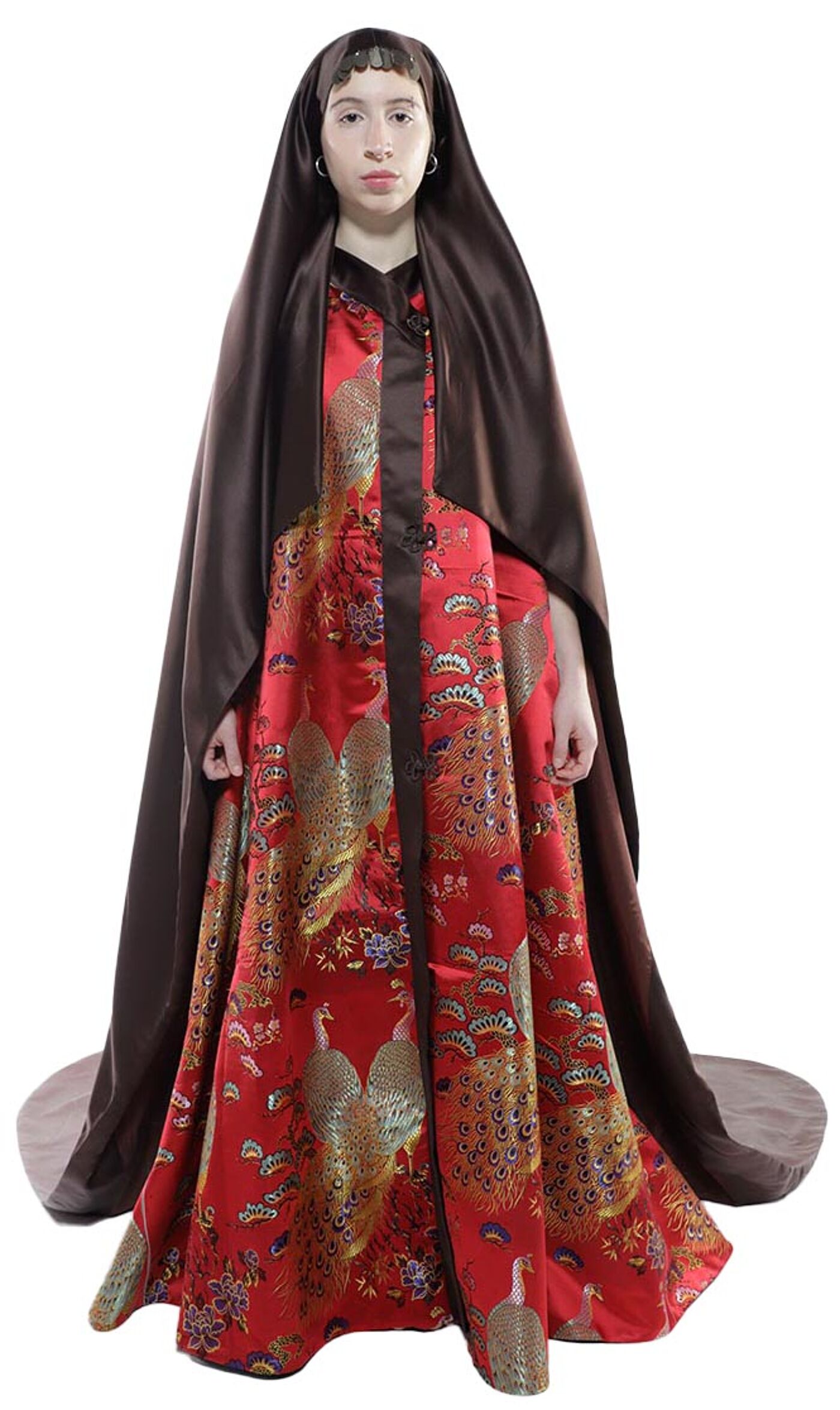 A person wearing a long, red and gold brocade dress with a brown satin cape stands against a white background.
