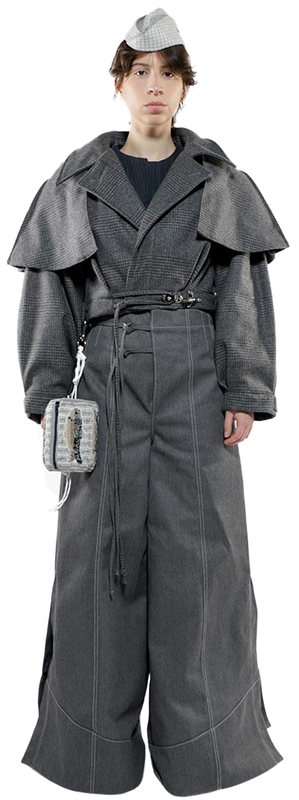 A person wearing a gray coat and matching wide-leg pants, a gray newsboy cap, and a small patterned pouch slung across their body stands against a white background.