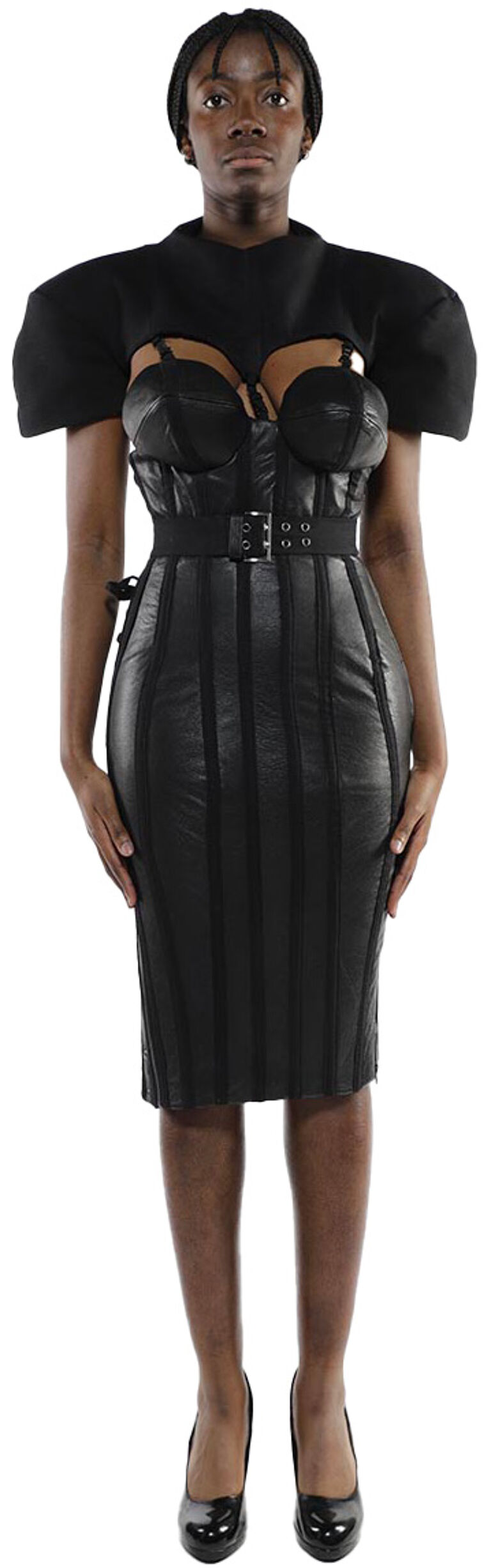 A dark-skinned model with short black hair wears a black fitted midi dress with shoulder pads and black high heels.