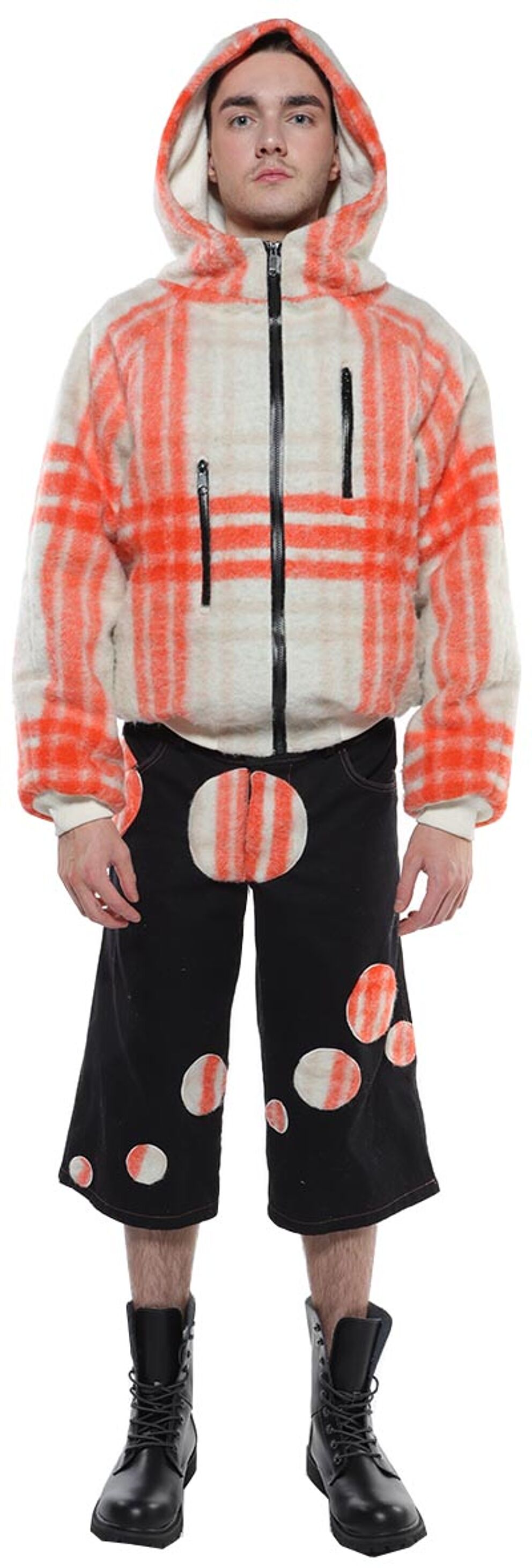 A person wearing a hooded orange and white plaid jacket, black shorts with orange polka dots, and black combat boots is shown standing against a white background.