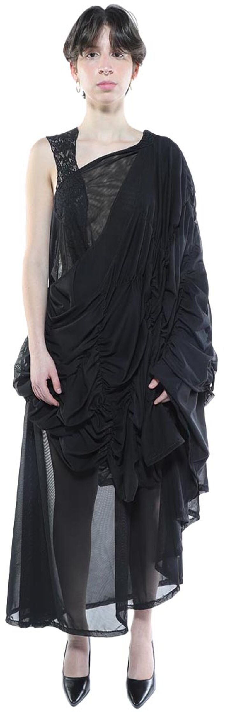 A young woman with short dark hair models a black, asymmetrical, sheer and ruffled dress with a lace overlay.