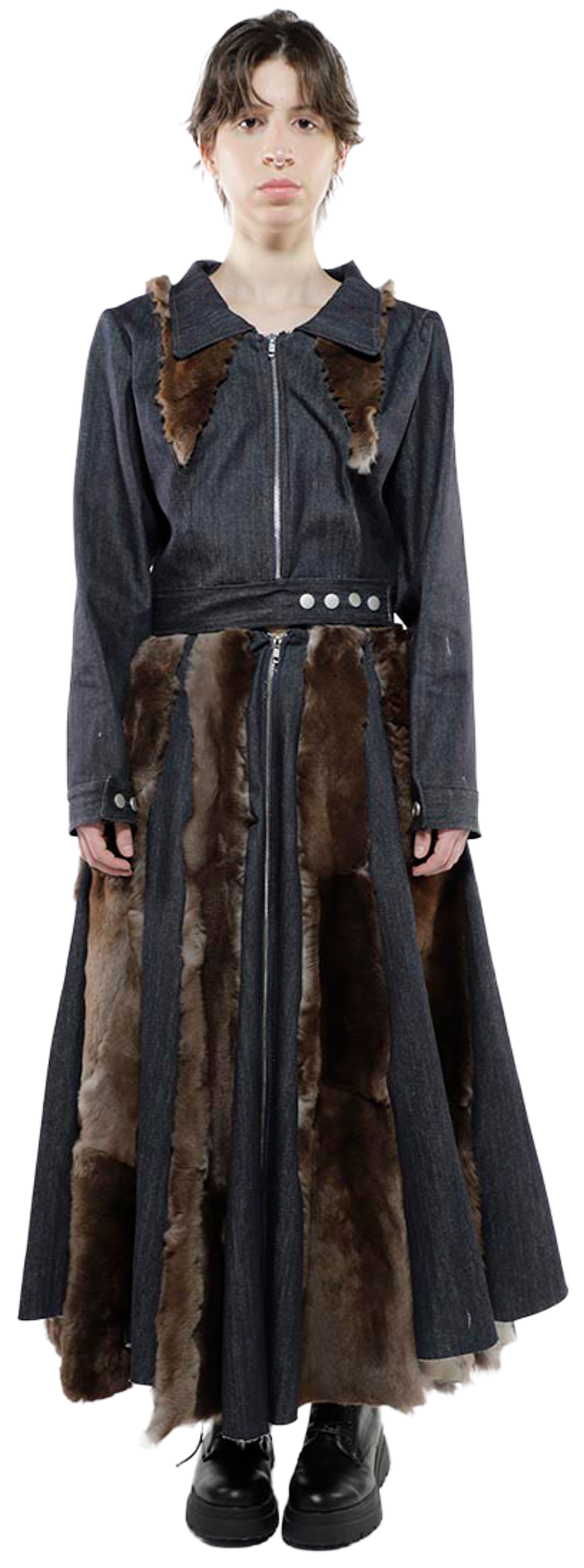 A full shot of a woman wearing a long dark denim dress with brown fur accents, standing against a white background.