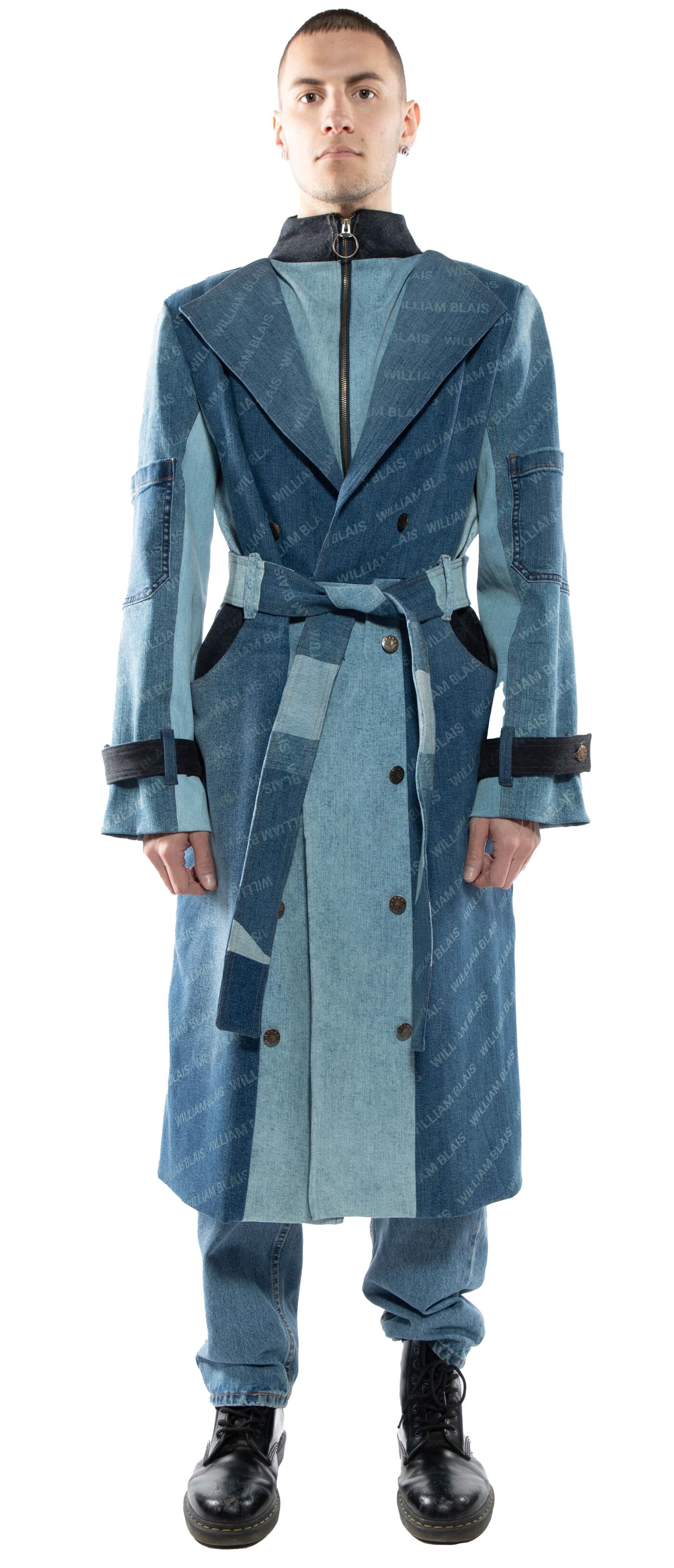 A full shot of a person wearing a long, light blue denim trench coat with dark blue accents and black boots.