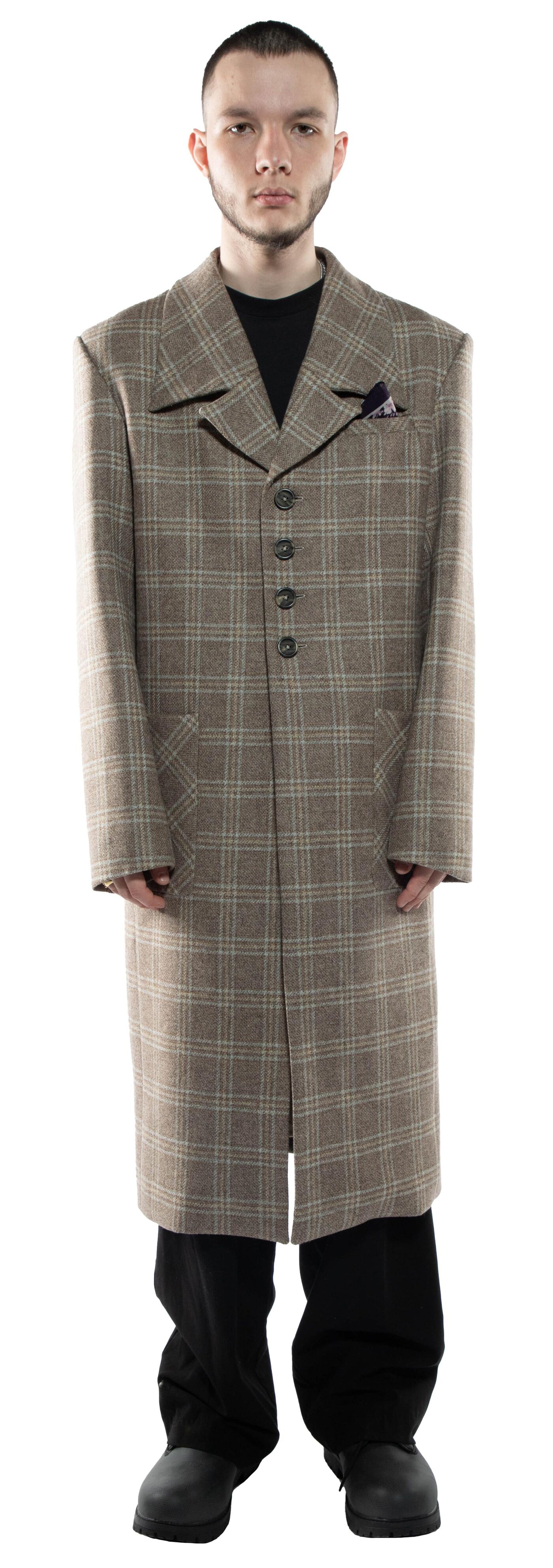 A man in a beige plaid overcoat stands against a white background.