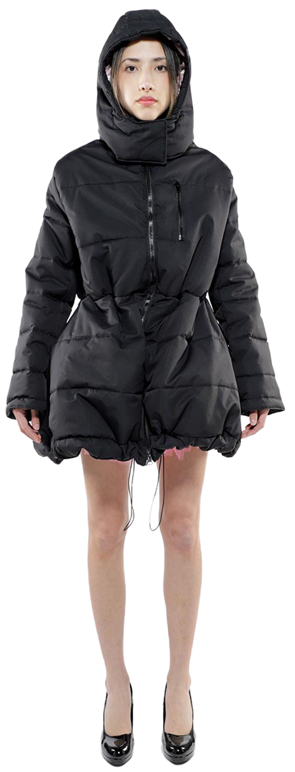A full shot of a young woman wearing a black puffer jacket with a hood, cinched at the waist, and black high heels.