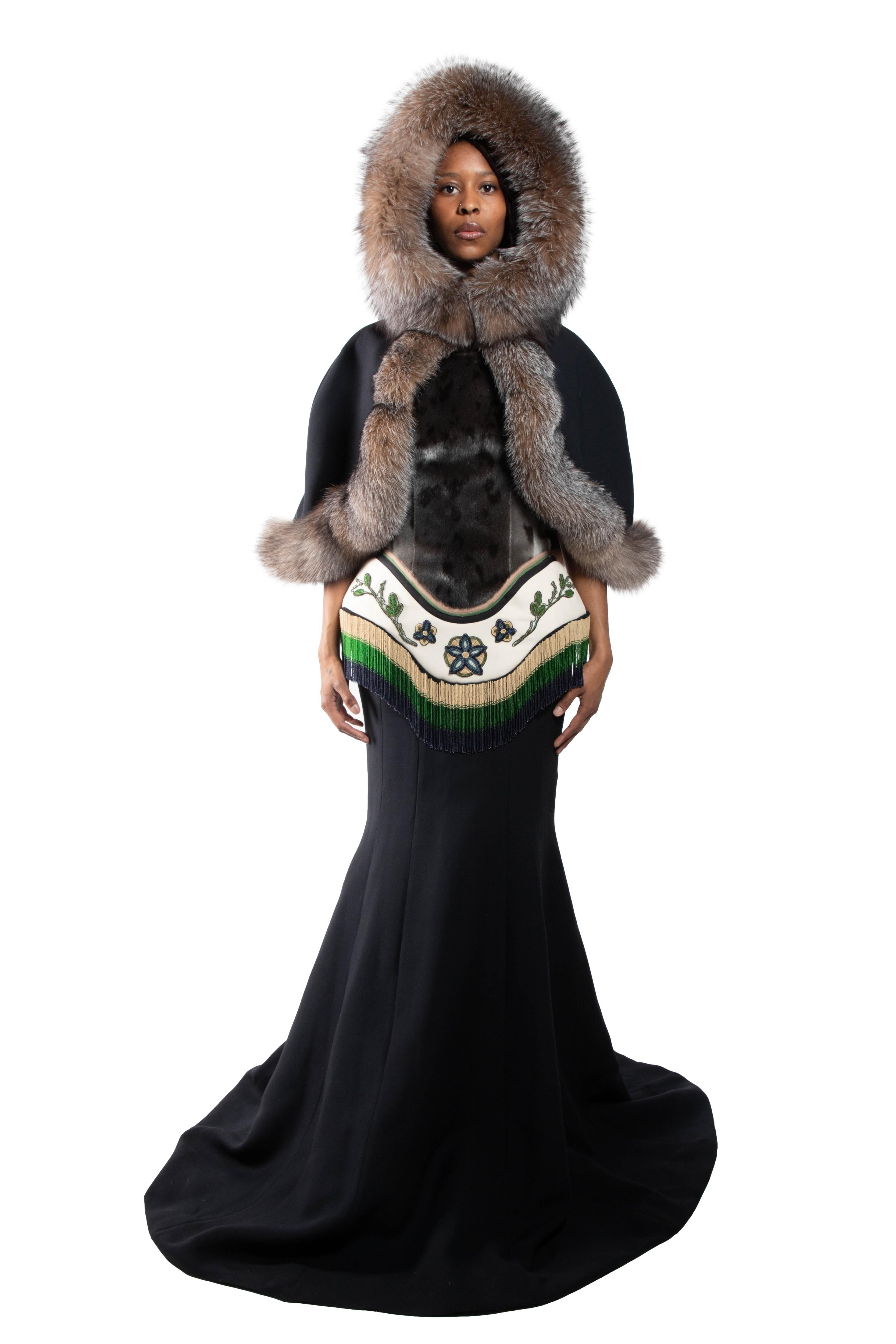 This woman is wearing a long black dress with a beaded and fur-trimmed bodice, and a large fur hood.