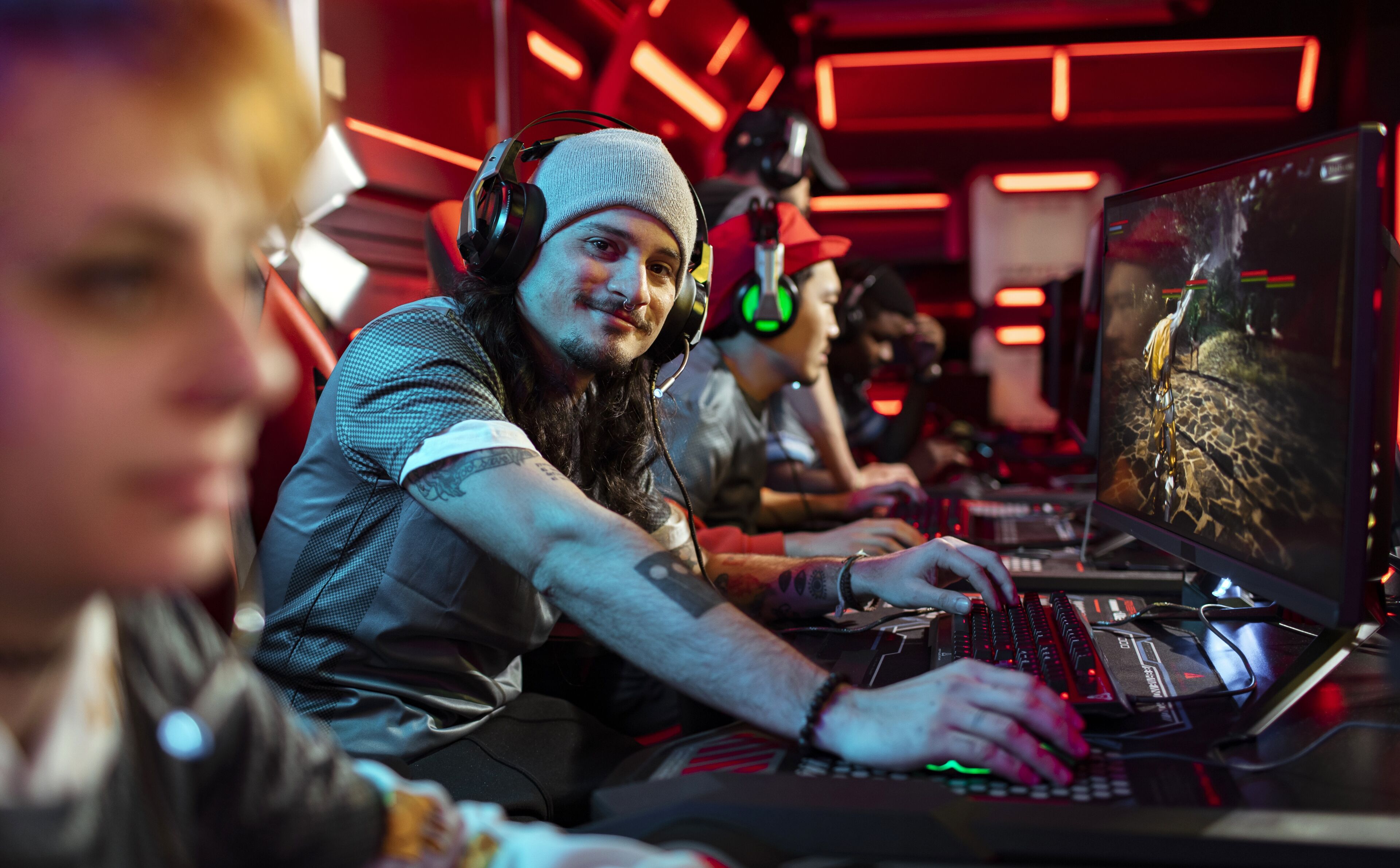 Gamers with headphones intensely focused on competitive video gaming at an esports event with a red neon-lit ambiance.