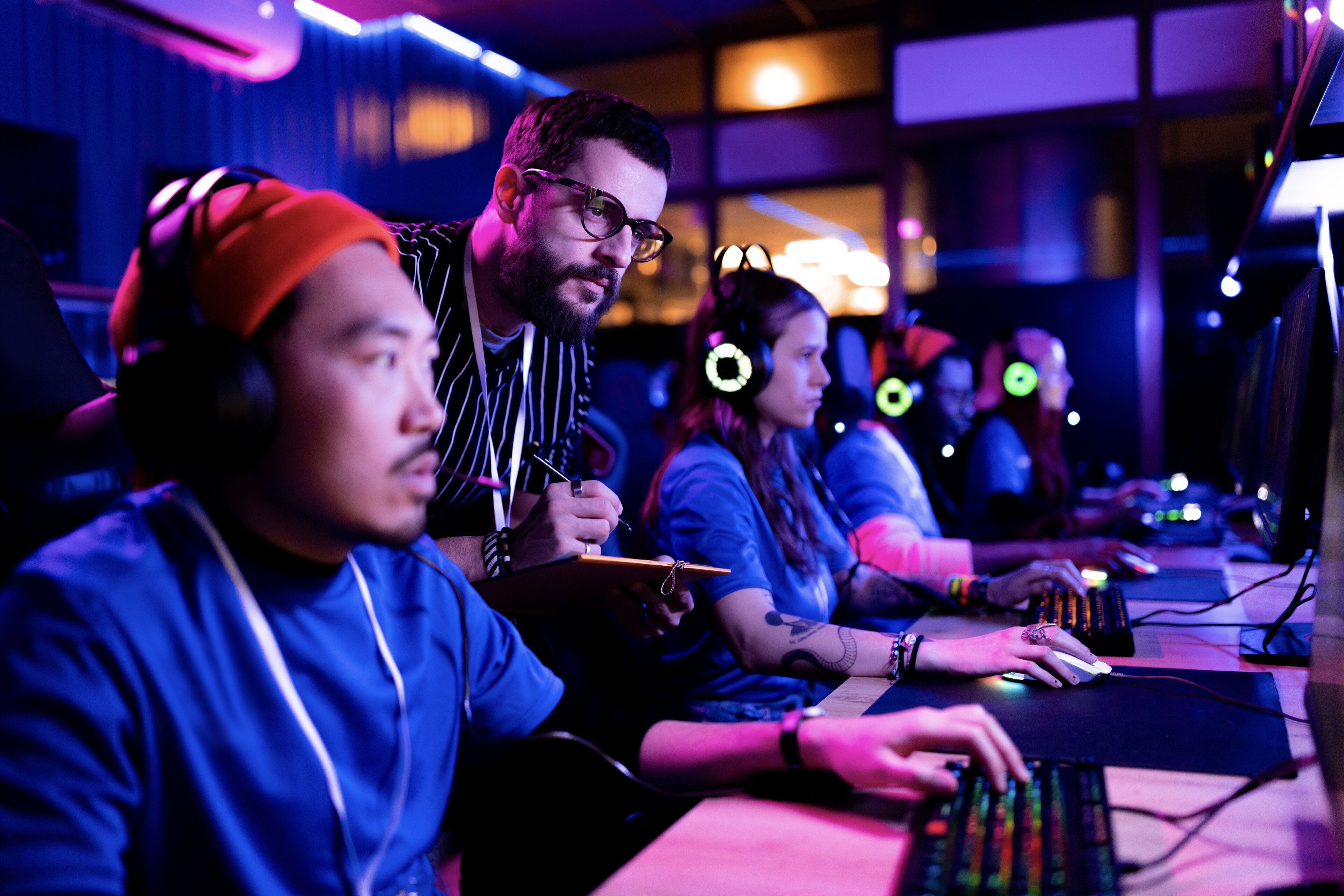 A focused esports team engaged in competitive play, with neon-lit headphones and intense expressions.