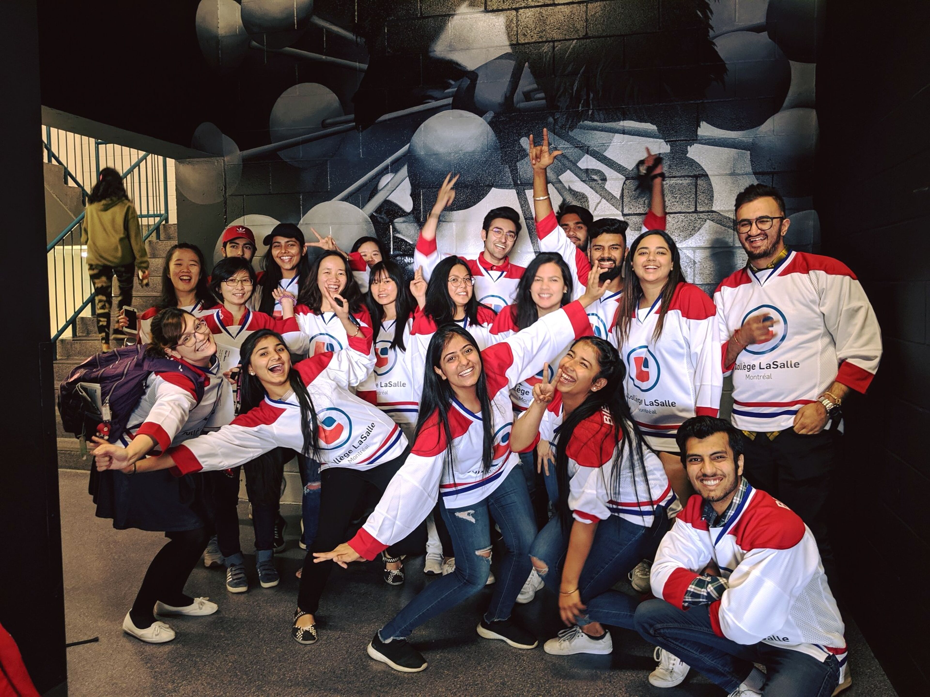 A joyful group of students in hockey jerseys posing for a celebration photo, with vibrant expressions.
