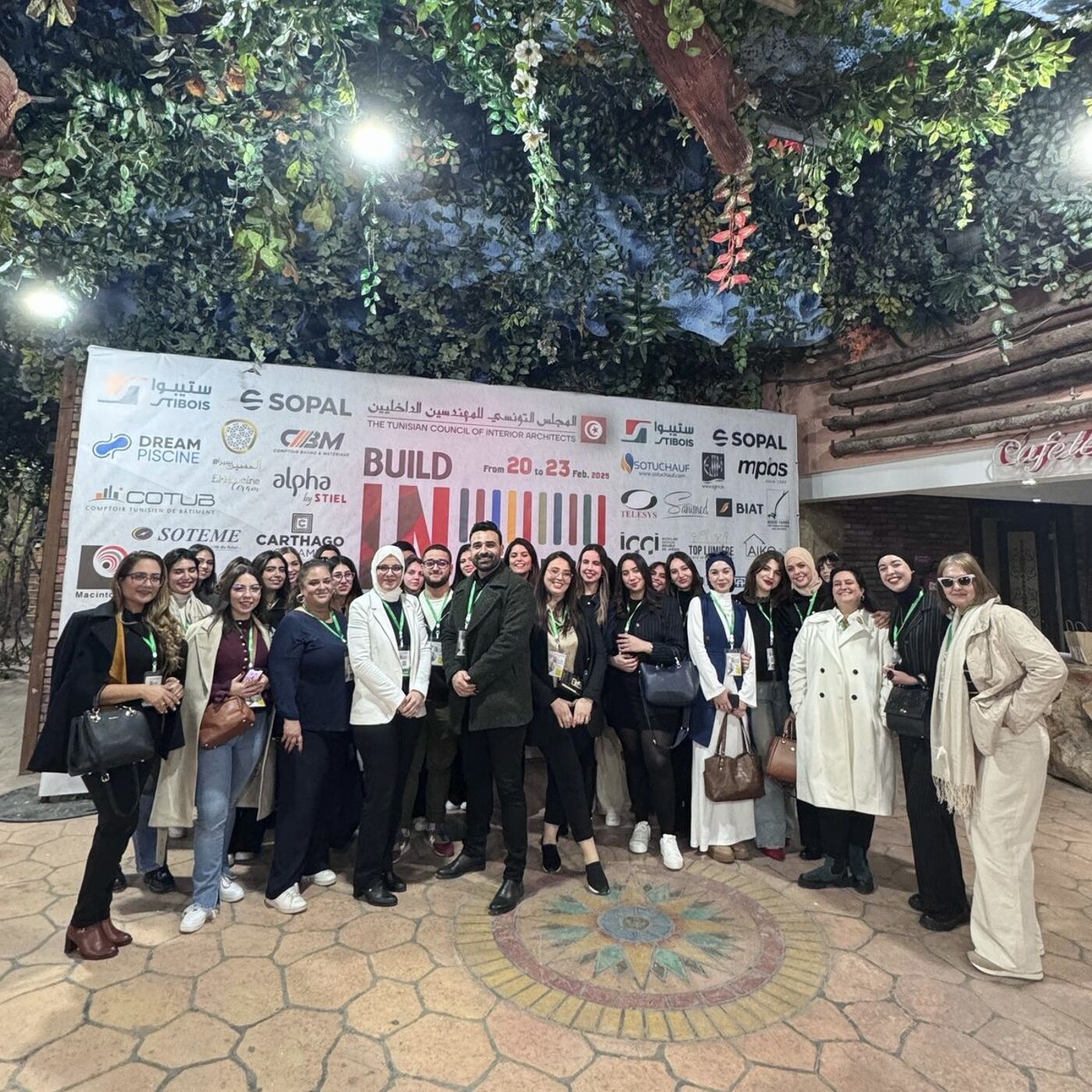 A large group of people pose for a photo in front of a banner advertising a "BUILD" event, many of them wearing professional attire.