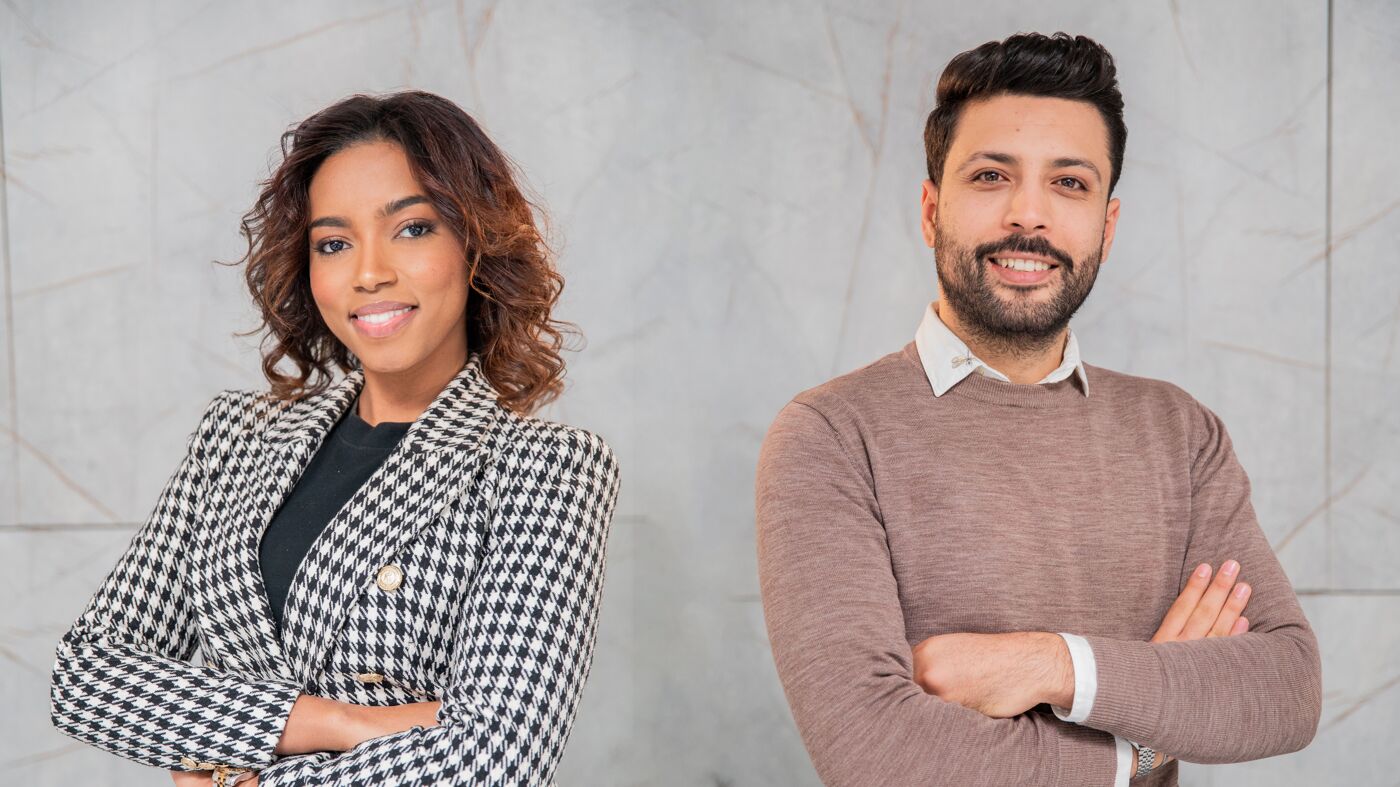 A confident man and woman standing back-to-back, dressed in business attire, conveying professionalism and teamwork.