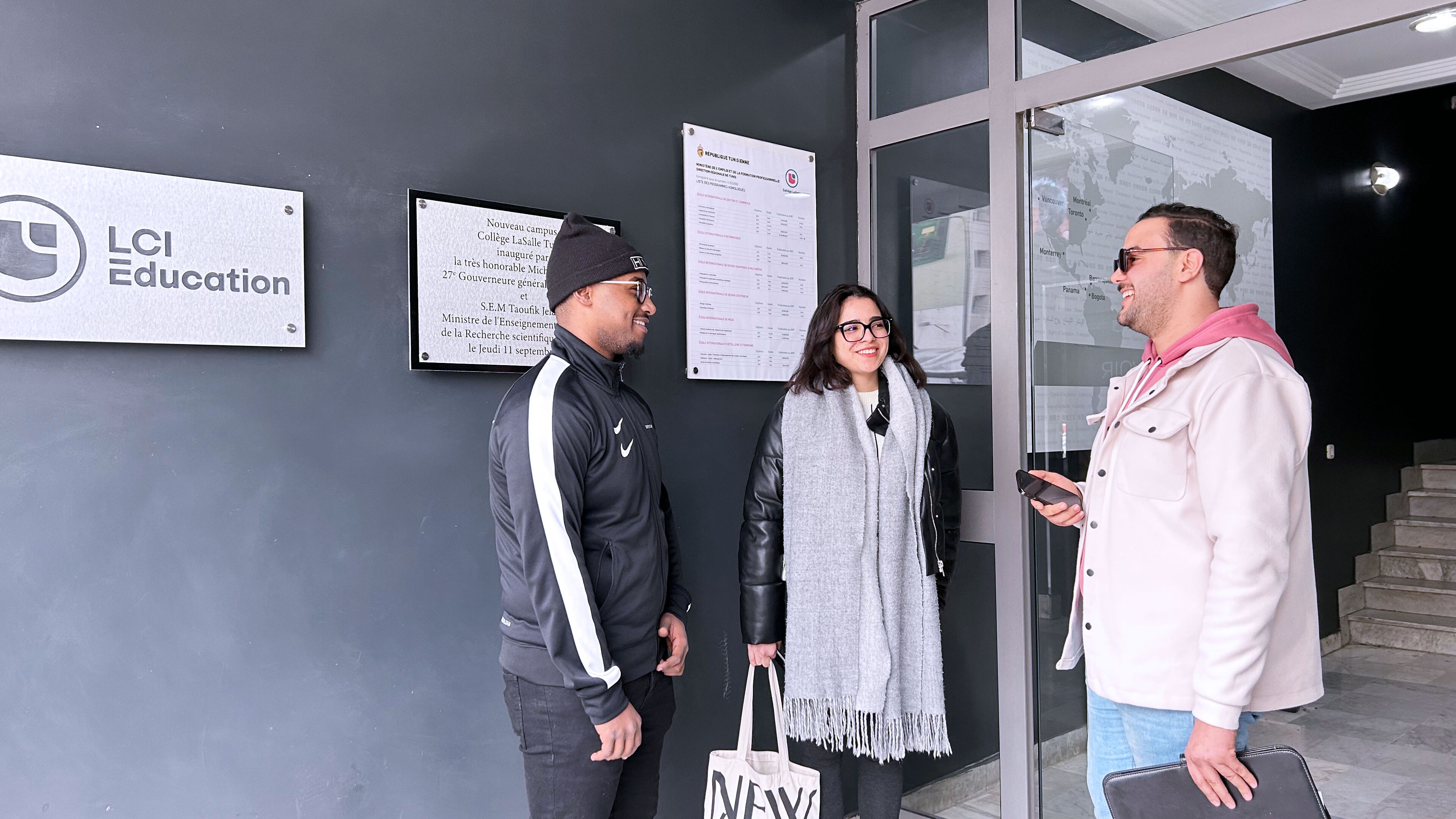  Three individuals engaging in a friendly conversation outside the LCI Education building, suggesting a collegial and welcoming educational environment.