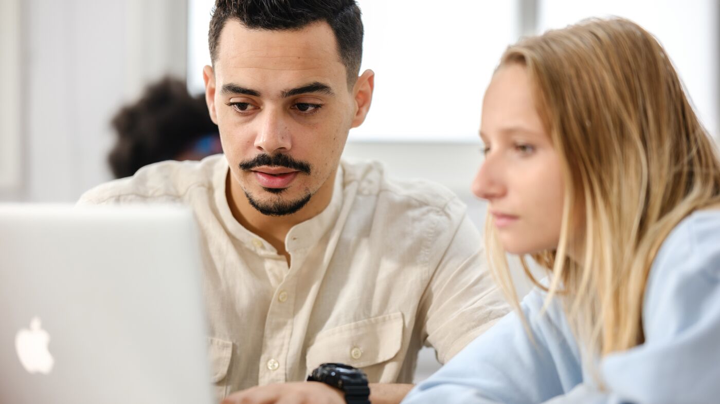 Two students concentrating on a project, with a laptop as a tool for their academic research and discussion.