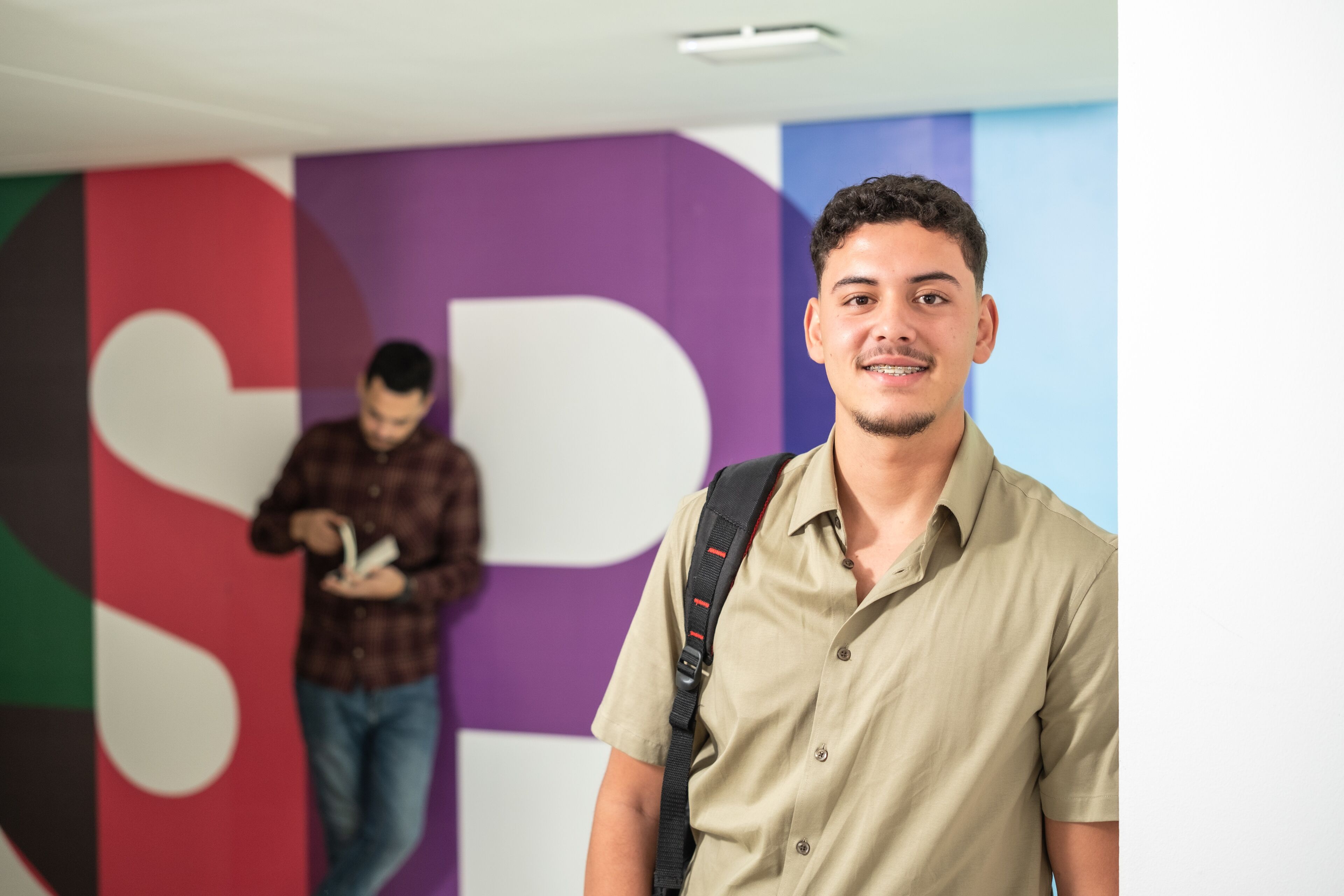 Mouad Erradaf, a student in the Bac+5 Management Program, stands in front of a colorful mural, embodying the vibrant spirit of campus life.