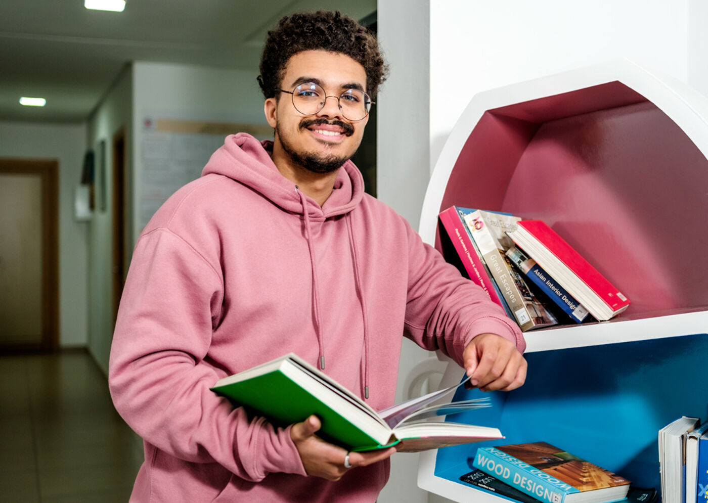 Étudiant souriant tenant un livre dans une bibliothèque