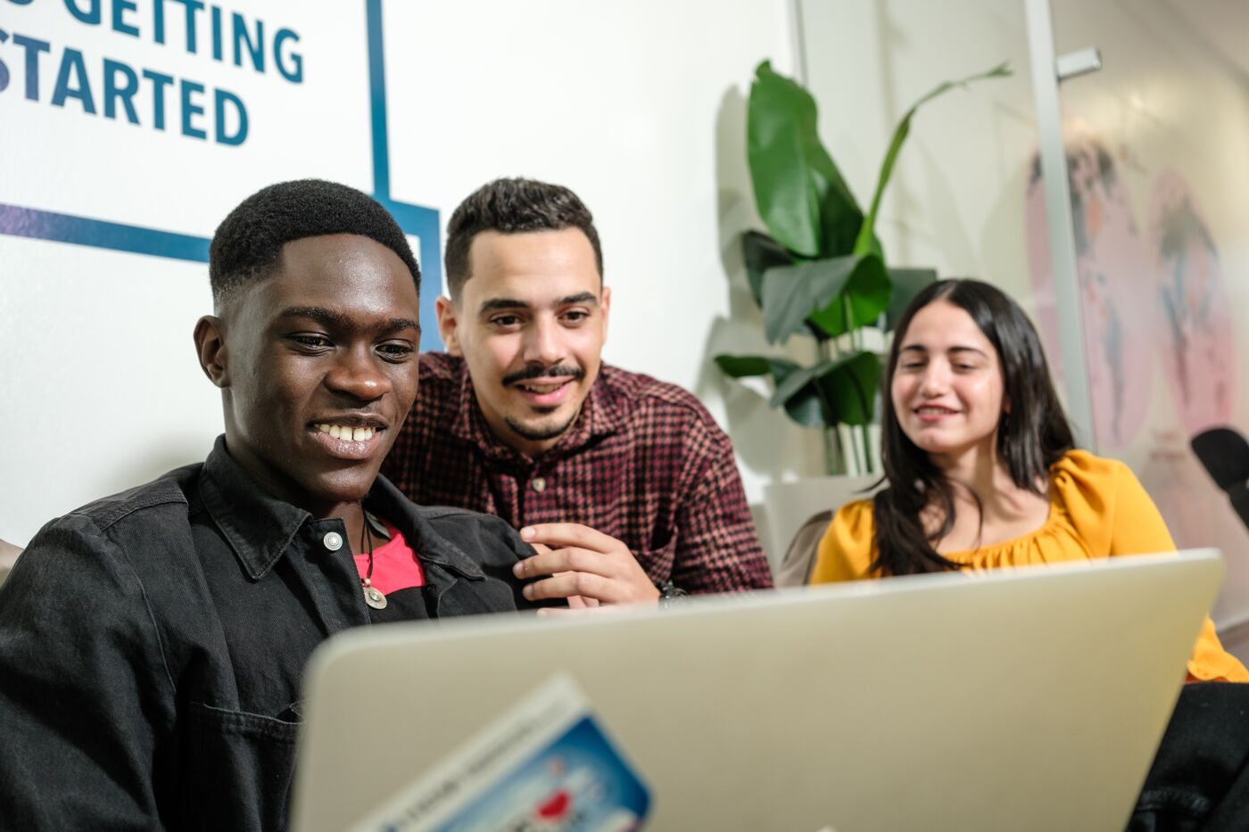 Three students with a laptop sharing a joyful learning moment.