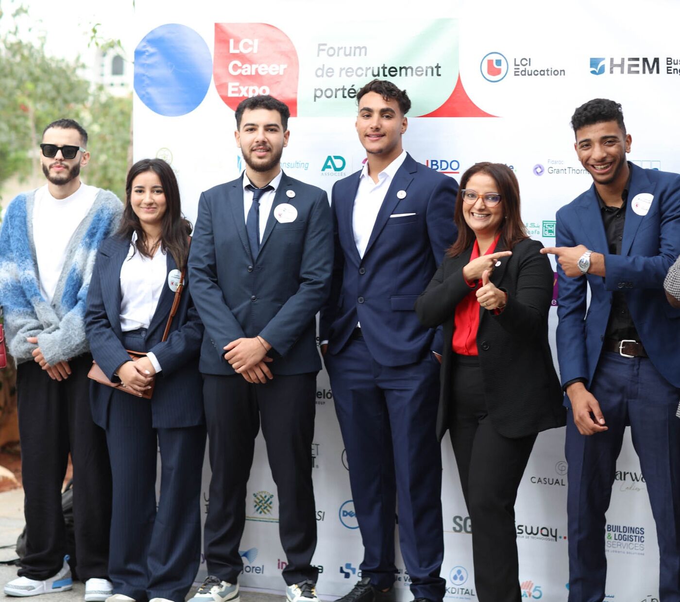 The image shows a group of young men and women posing together for a picture, likely at a conference or event.