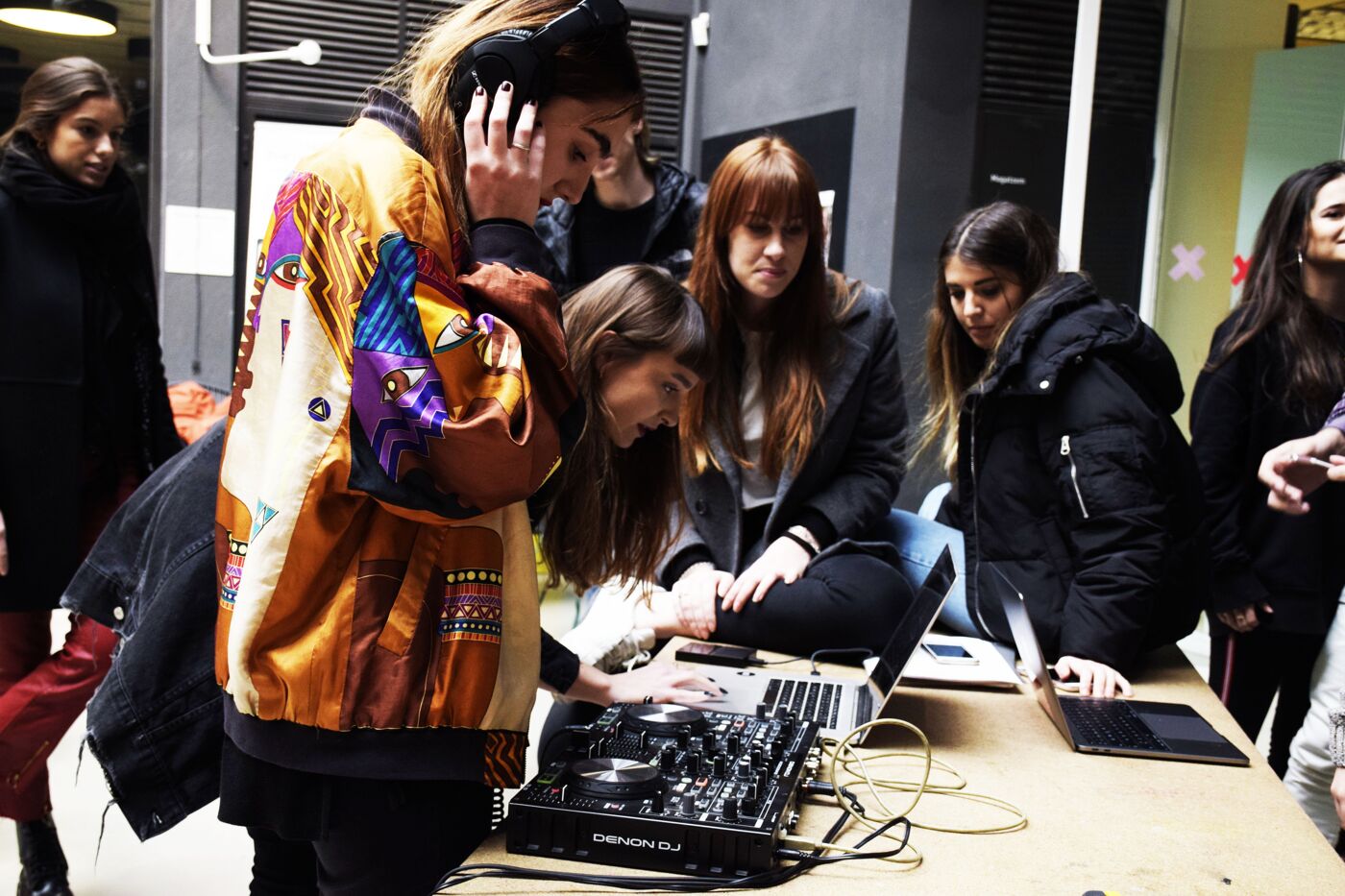 Students interact with DJ equipment during an event for prospective students in a vibrant campus setting.