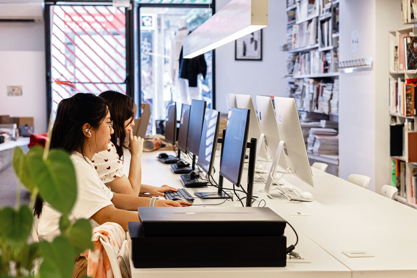 Individuals deeply engrossed in research at computers in the well-lit, modern interior of a public library.