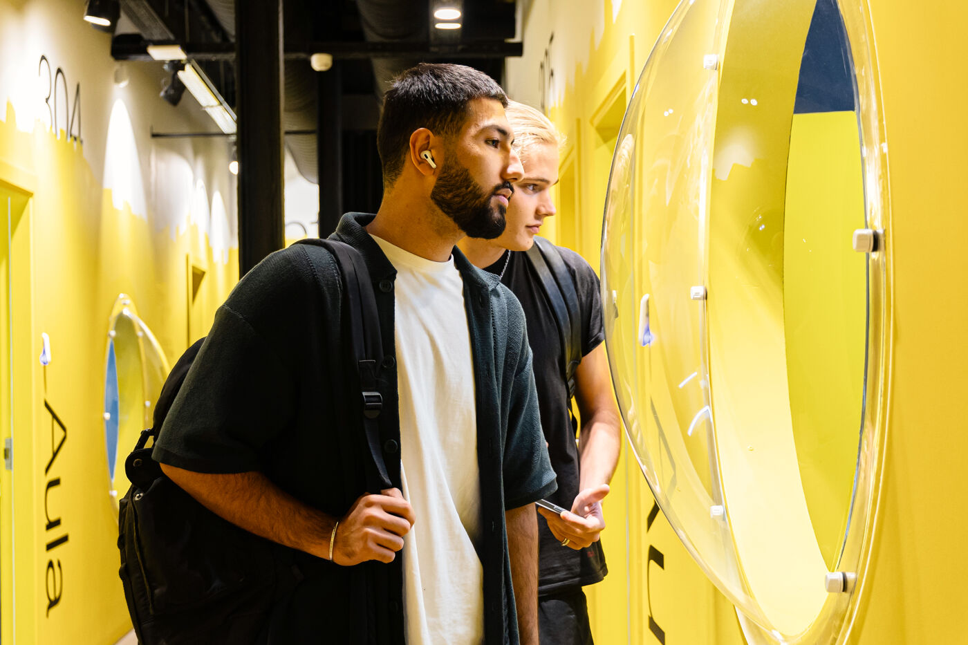 Two men examining interactive displays at a modern, brightly colored exhibit.