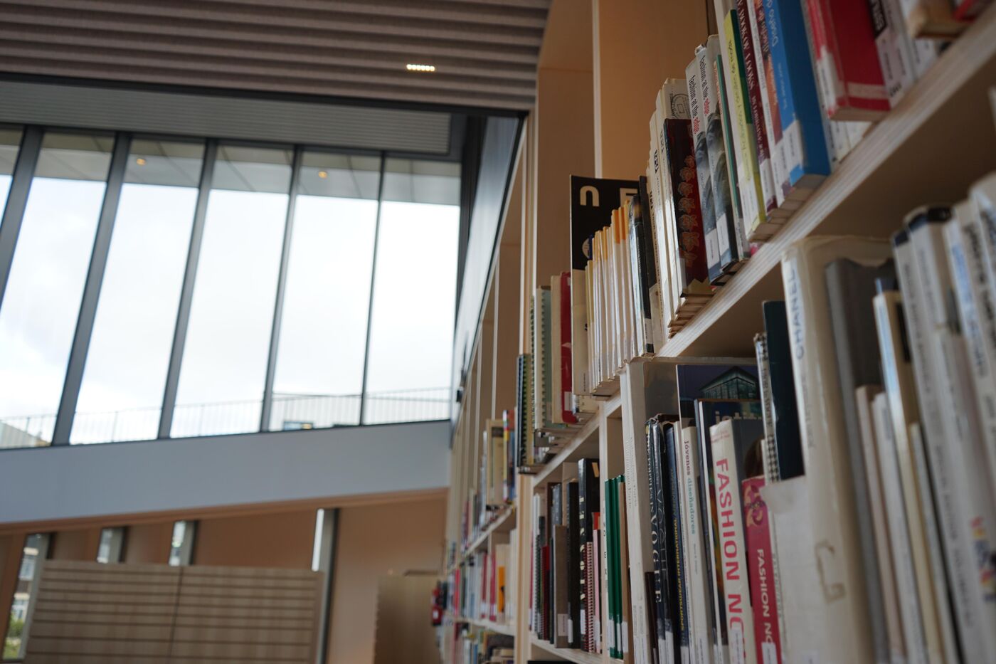 The image shows a large bookshelf filled with numerous books, likely in a library or a bookstore. The books are organized on the shelves, and the bookshelf is located in a room with a glass ceiling.