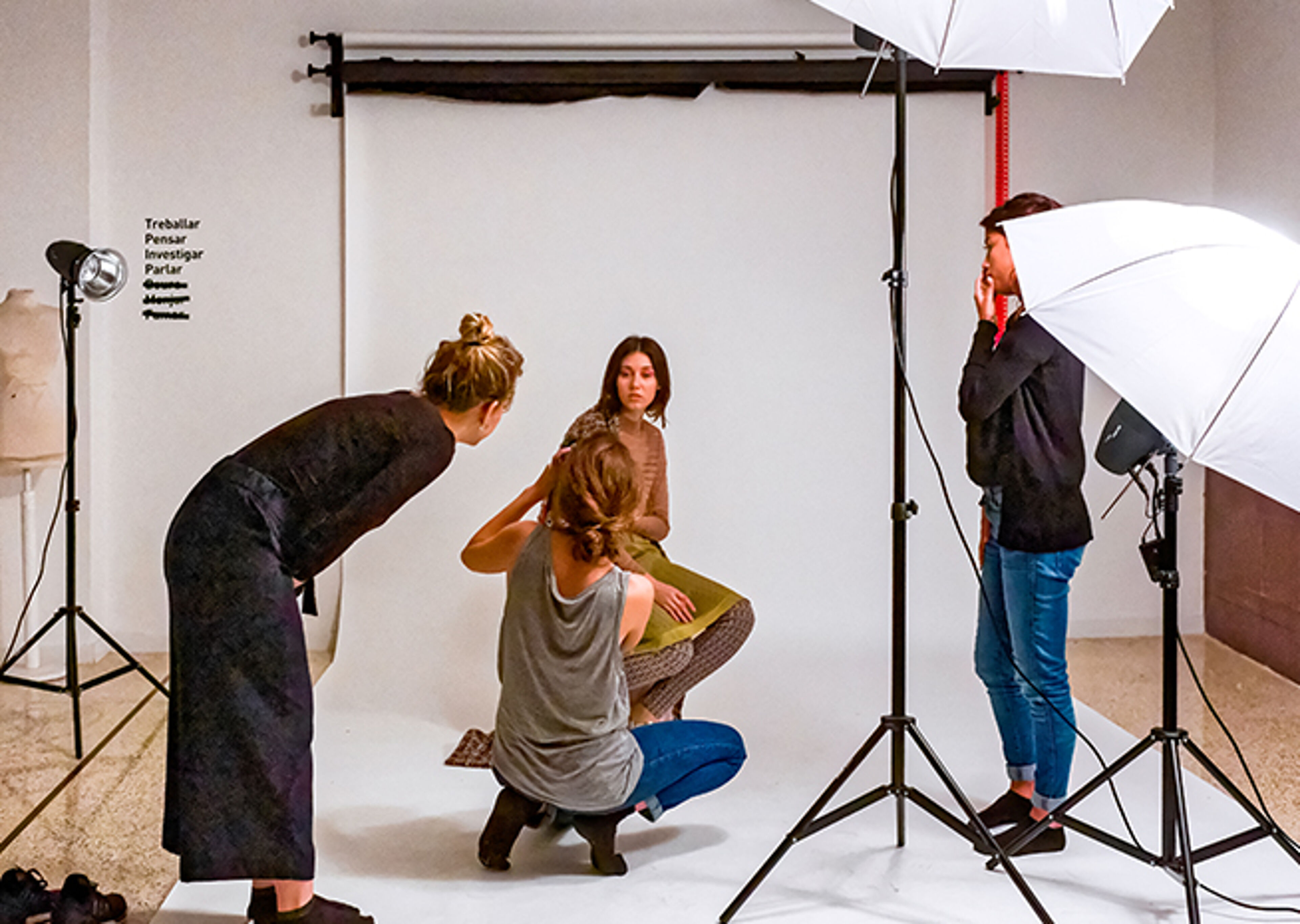 Behind-the-scenes view of a photo shoot with a photographer, model, and stylist working under studio lighting.