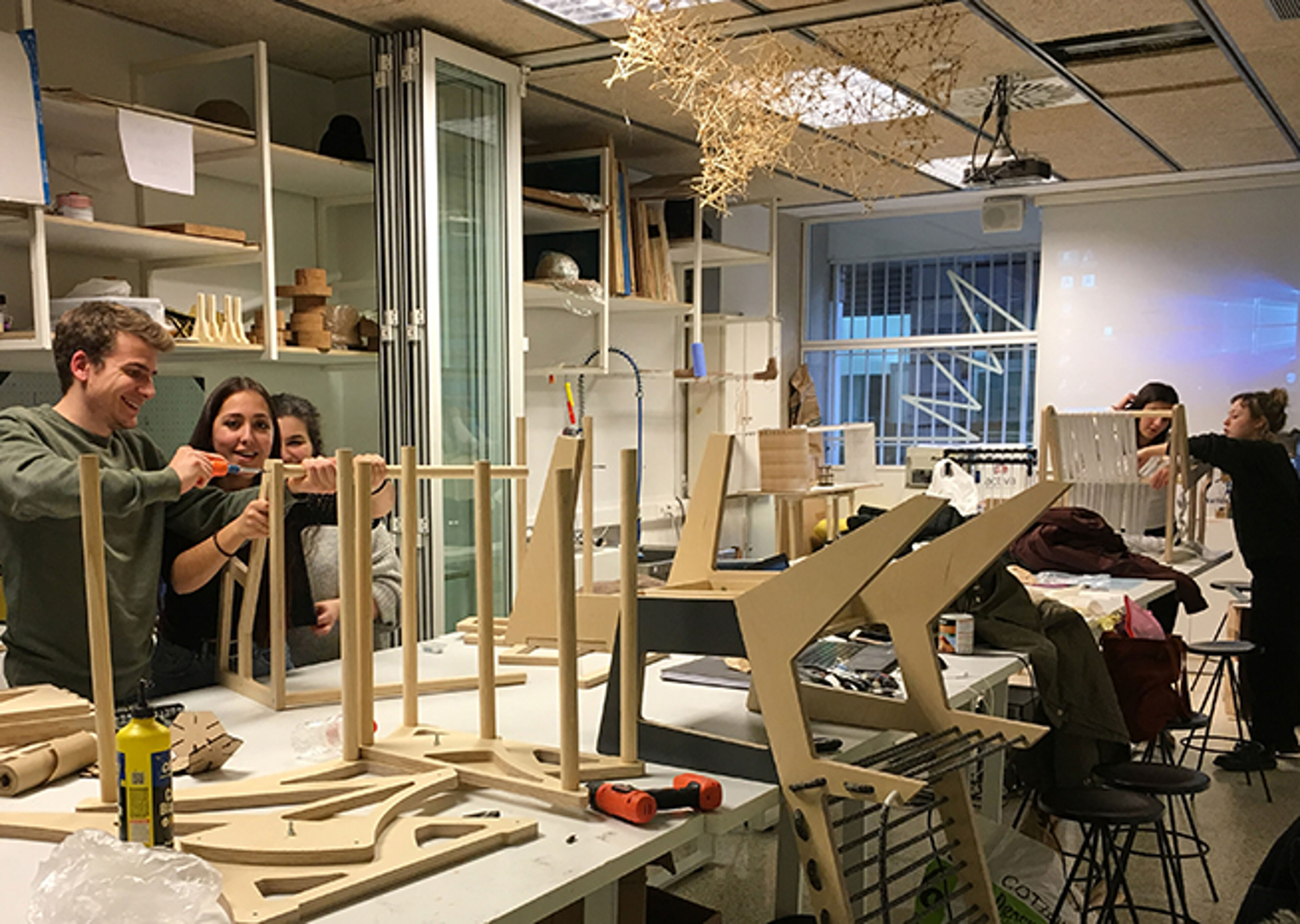Design students actively engaged in a workshop, crafting models with various tools and materials.
