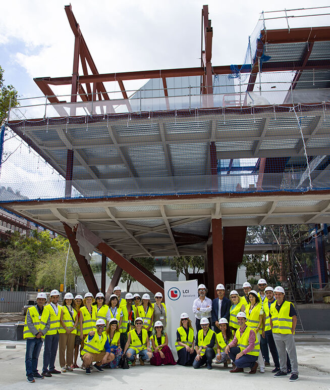 Un grupo de profesionales con equipo de seguridad frente a un edificio en construcción con andamios.