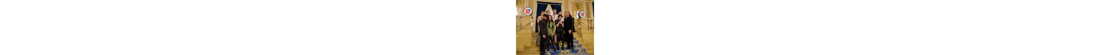 Un grupo alegre vestido de gala posa en la escalera de un lugar opulento, adornado con el logo de LCI.