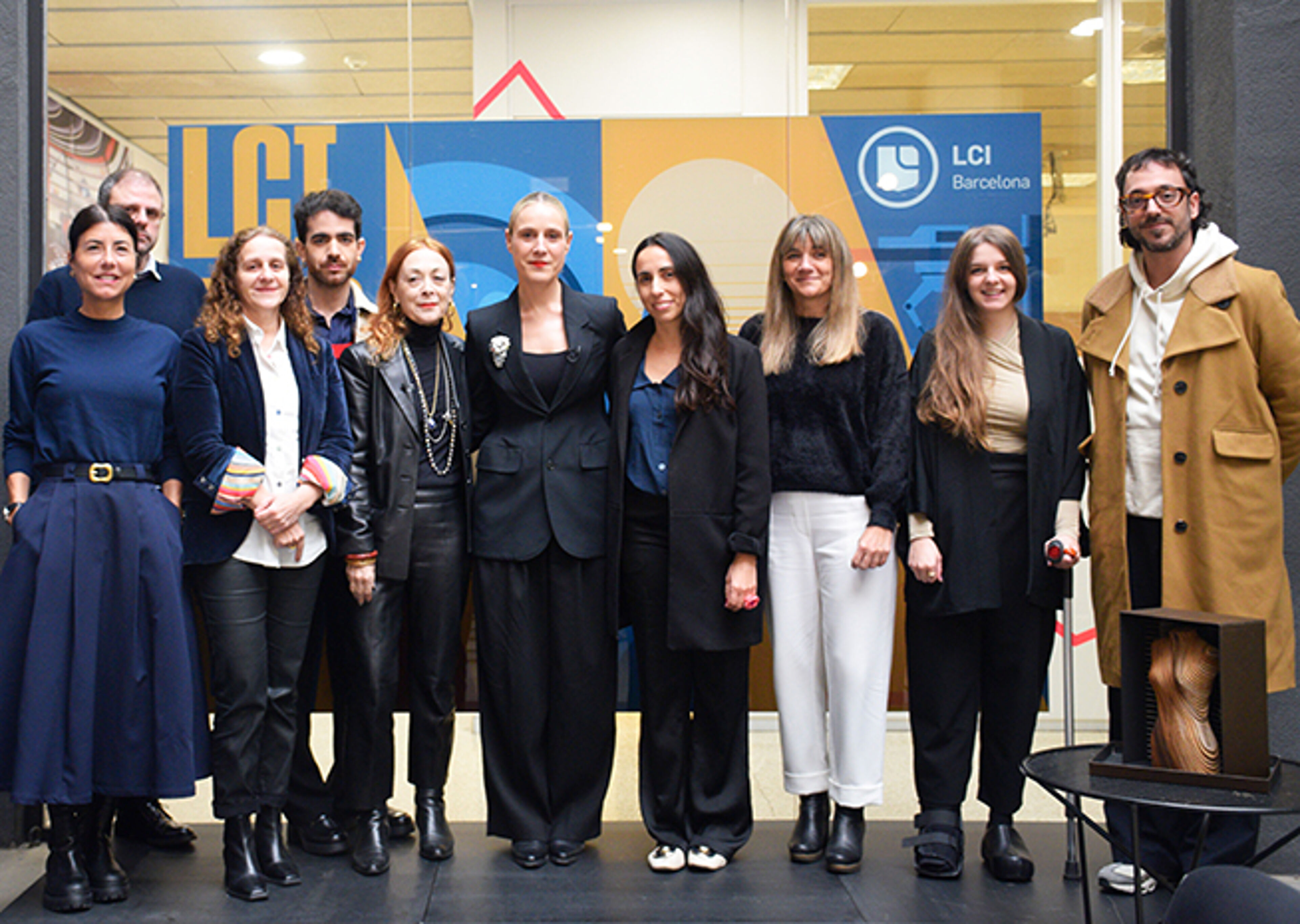  A group of professionals posing together for a team photo at LCI Barcelona, displaying a mix of casual and business attire.