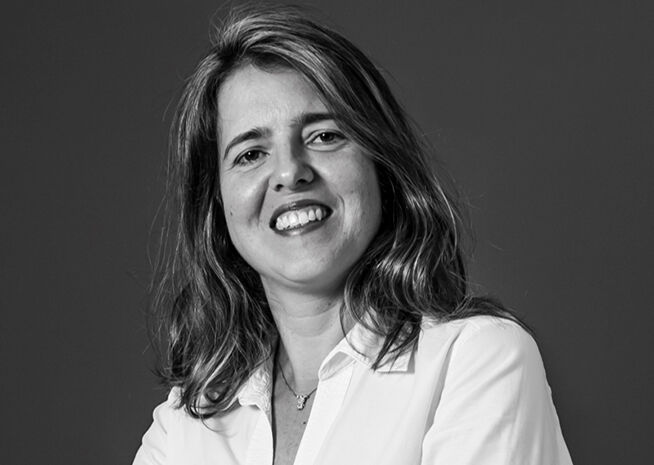 Black and white image of a joyful woman with shoulder-length hair, wearing a white shirt."