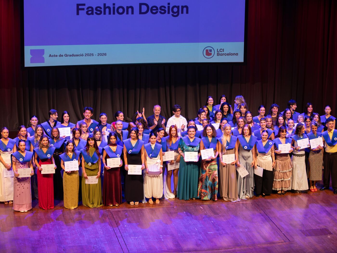 This is a graduation event with many students posing for a group photo holding their certificates.