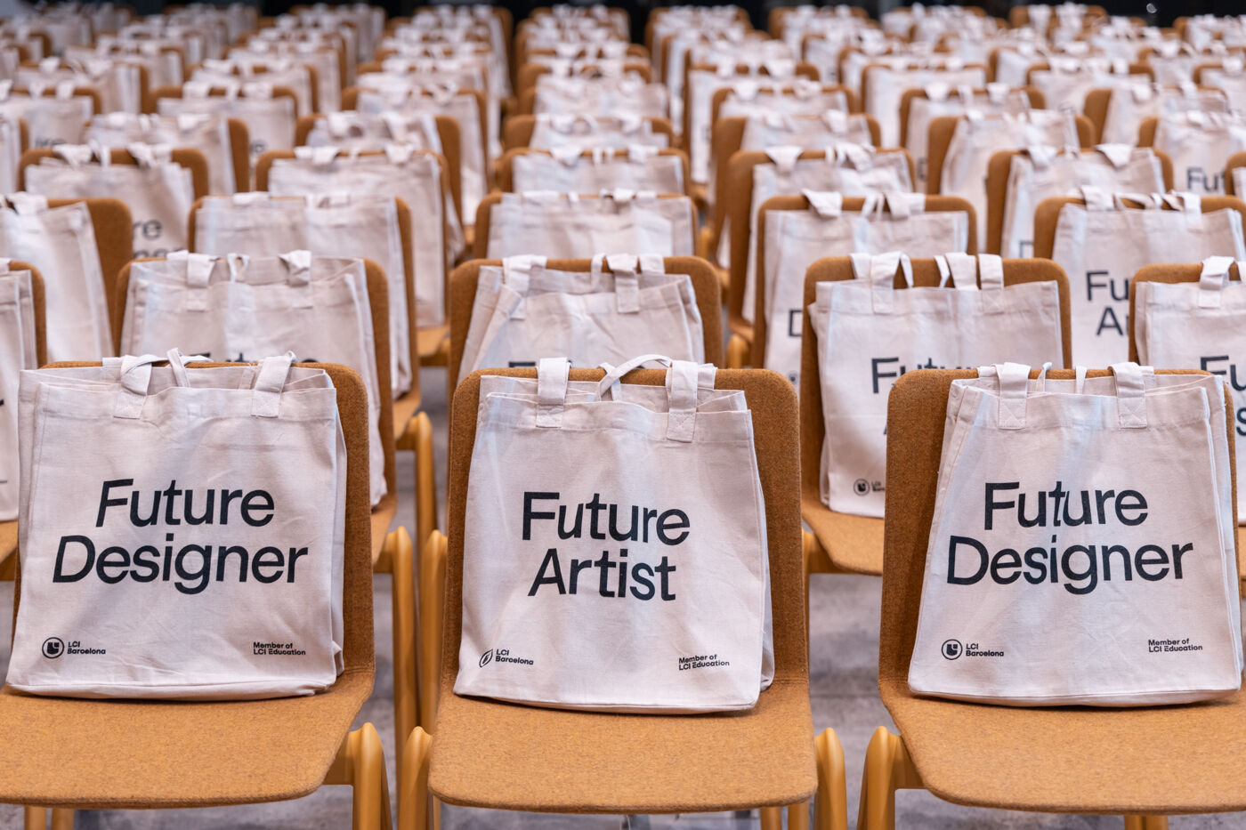 Rows of chairs are neatly arranged, each holding a white tote bag with "Future Designer" or "Future Artist" printed on them, suggesting a creative event or workshop.