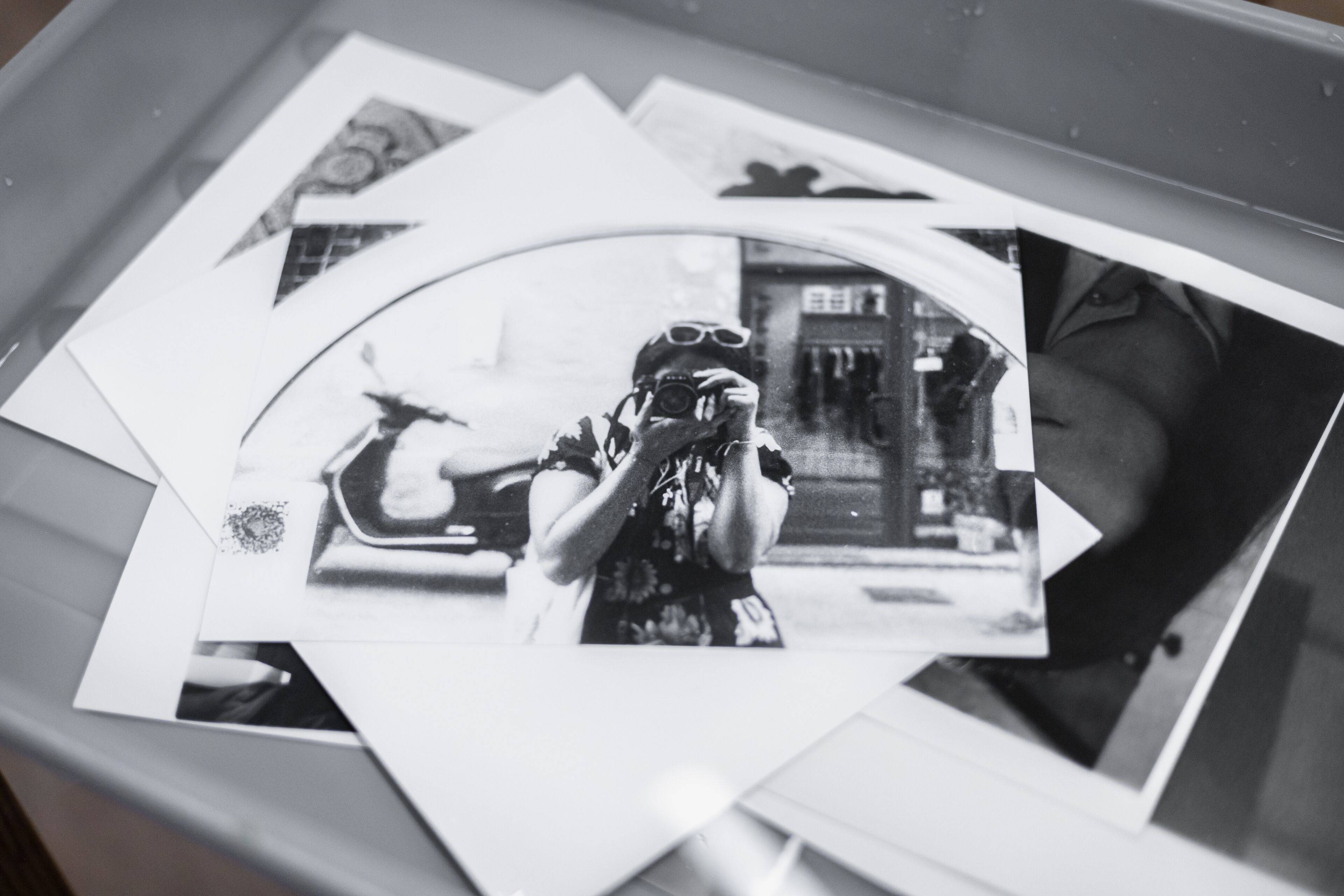 A collection of black and white photos, with a central image capturing the photographer's reflection in a mirror.