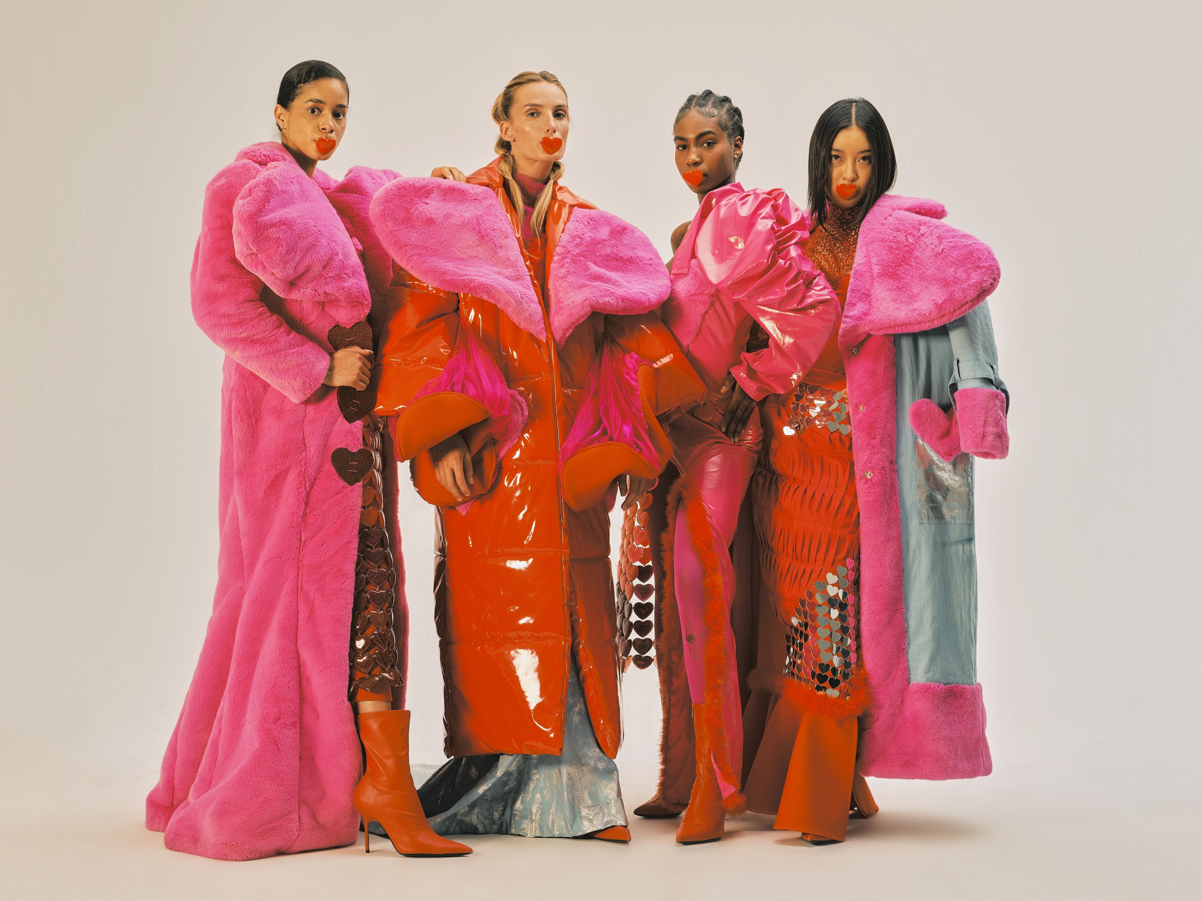 Four models striking a pose in bold, colorful outerwear with a mix of textures.