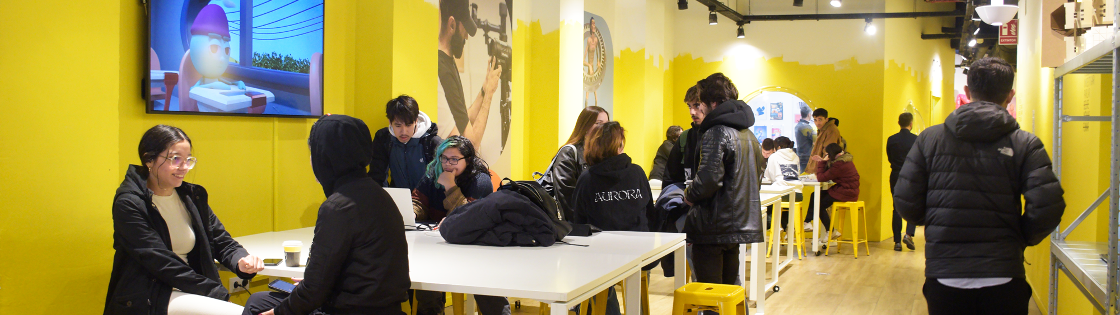 Individuos colaboran y socializan en un espacio de trabajo brillante y contemporáneo con acentos amarillos.