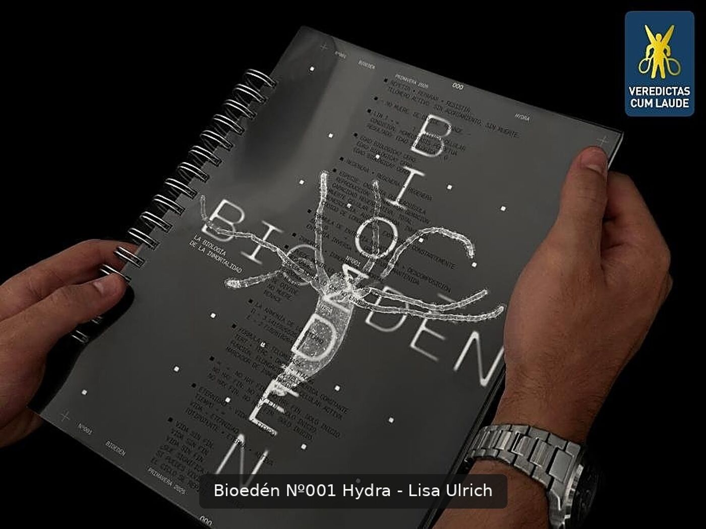 A hand holds a notebook titled "Bioedén N°001 Hydra - Lisa Ulrich", featuring a drawing of a hydra and large "BIO" text.