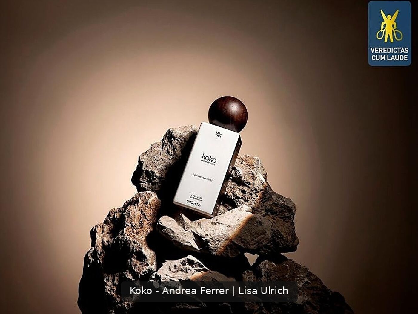 A product box for Koko rests on rocks, topped with a brown sphere. The background features a gradient beige hue.