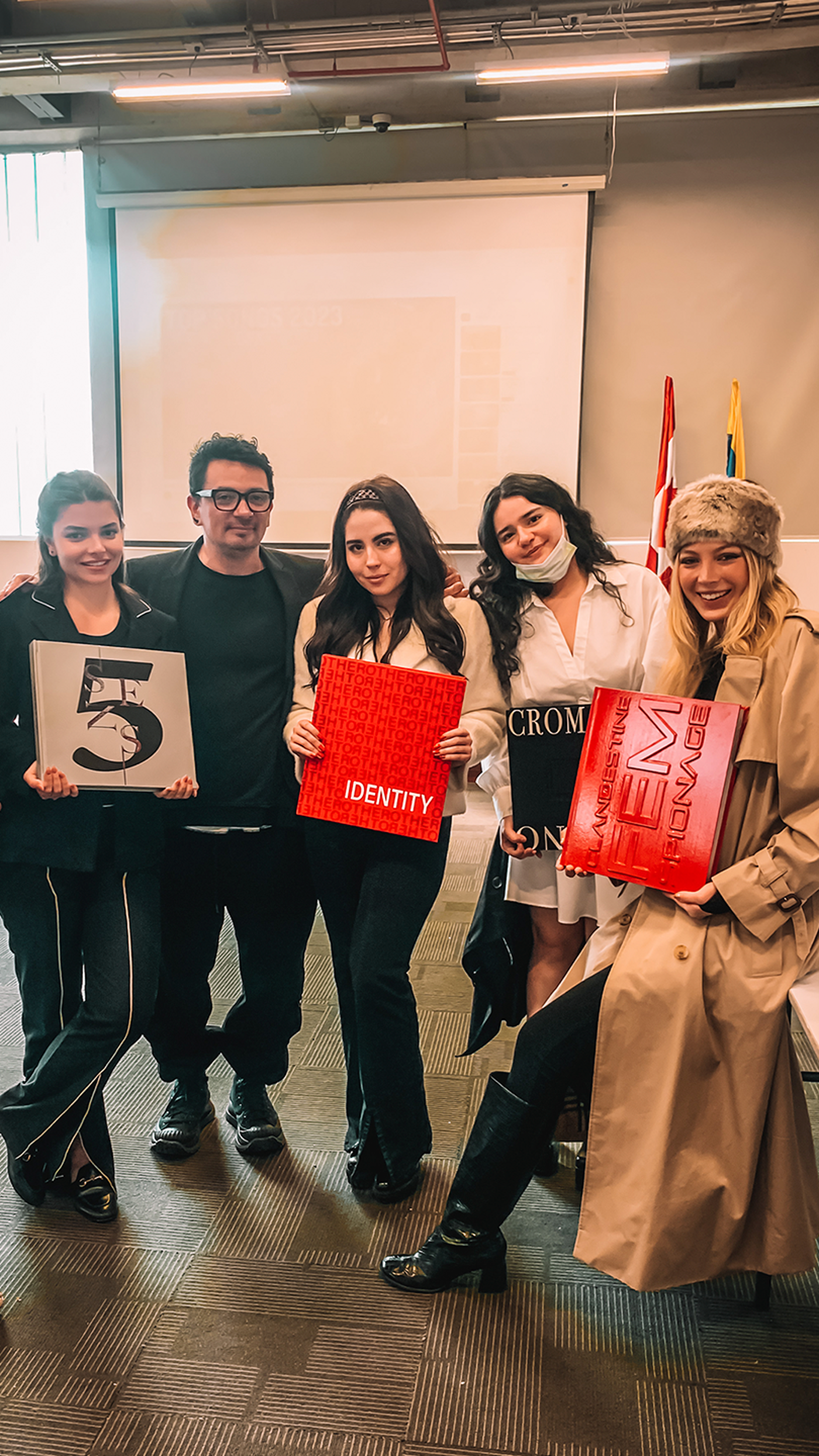 Four students holding fashion design books pose with their mentor.