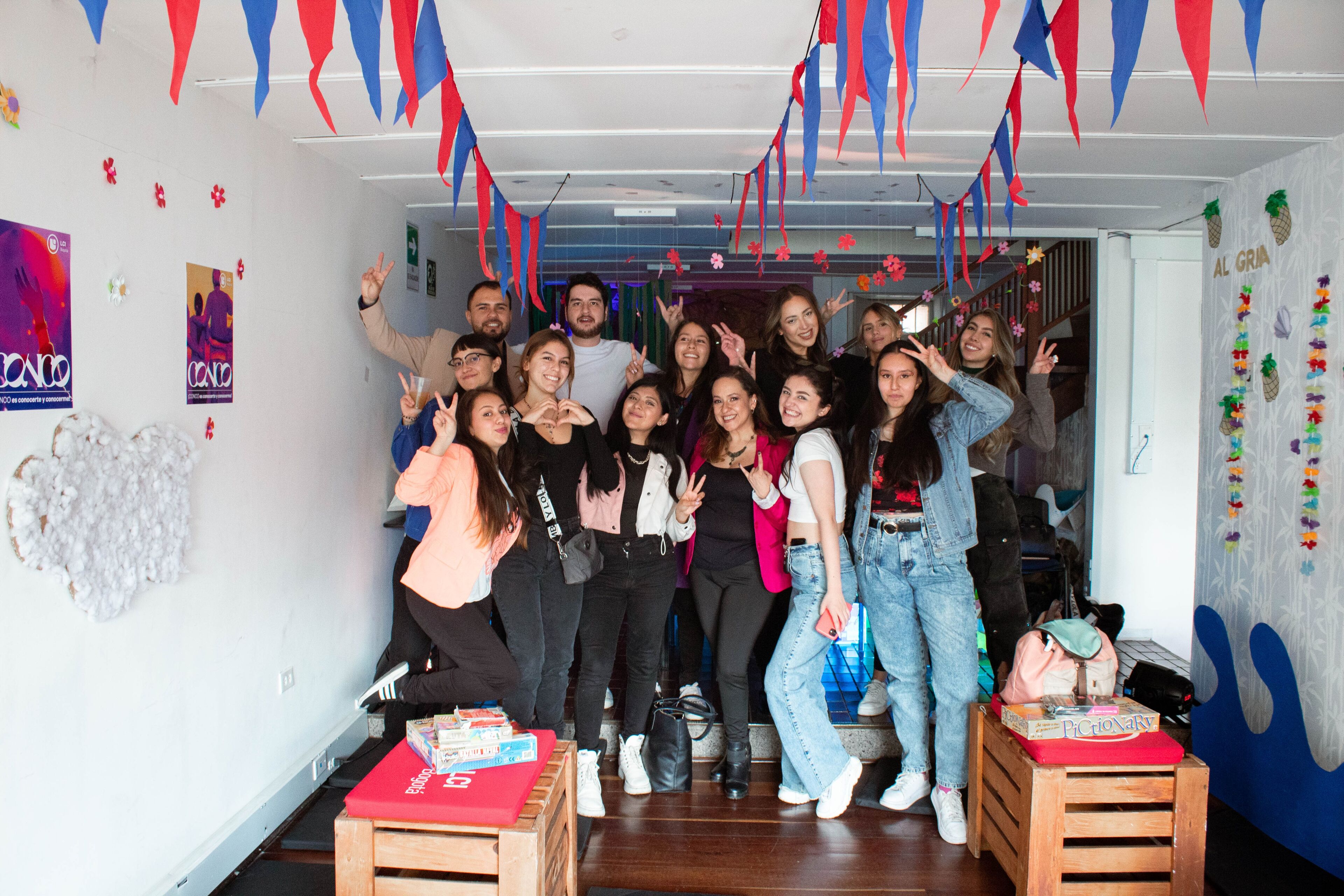 A group of cheerful colleagues posing at a festive office party, decorated with colorful streamers and flags.