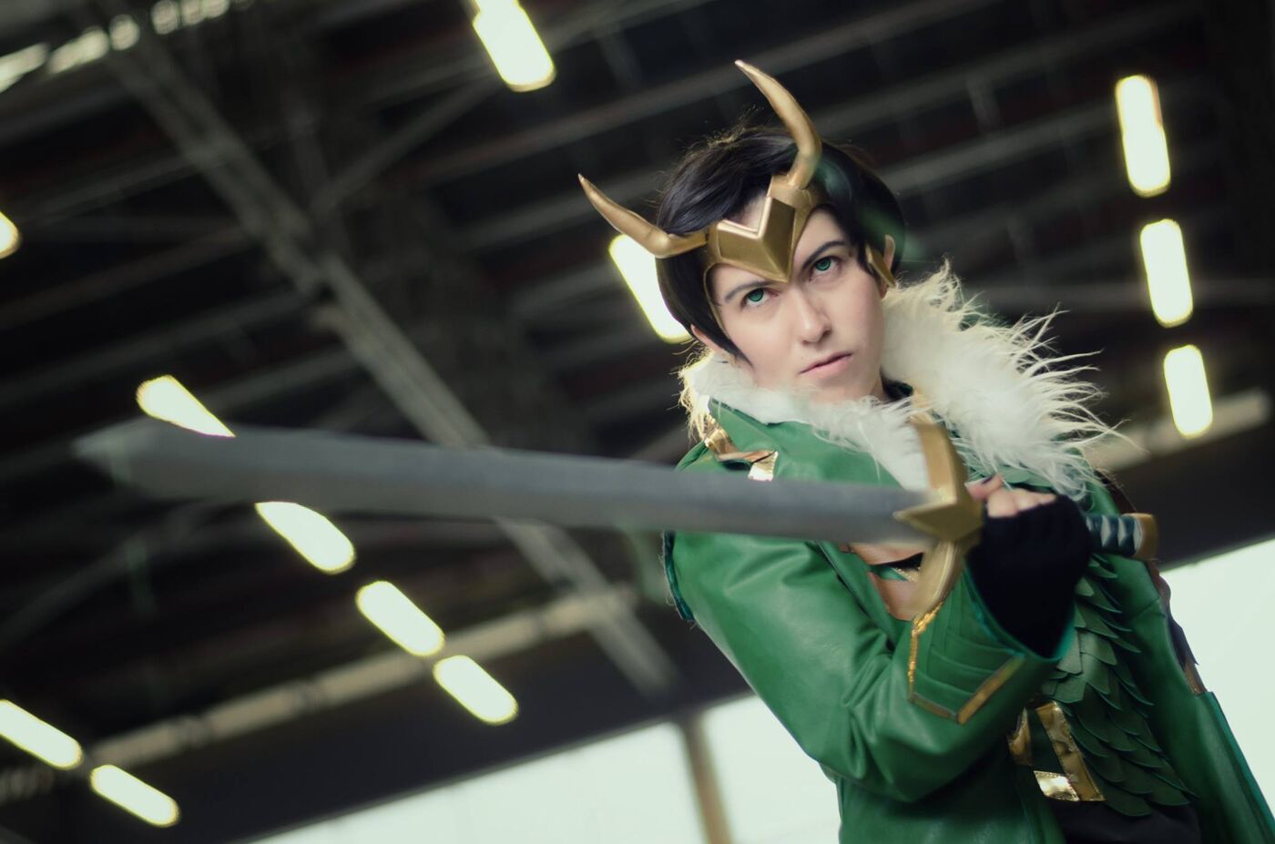 This image features a cosplayer dressed as Loki, the Norse god of mischief, holding a sword with a determined expression. The costume includes Loki's iconic horned helmet and green attire.